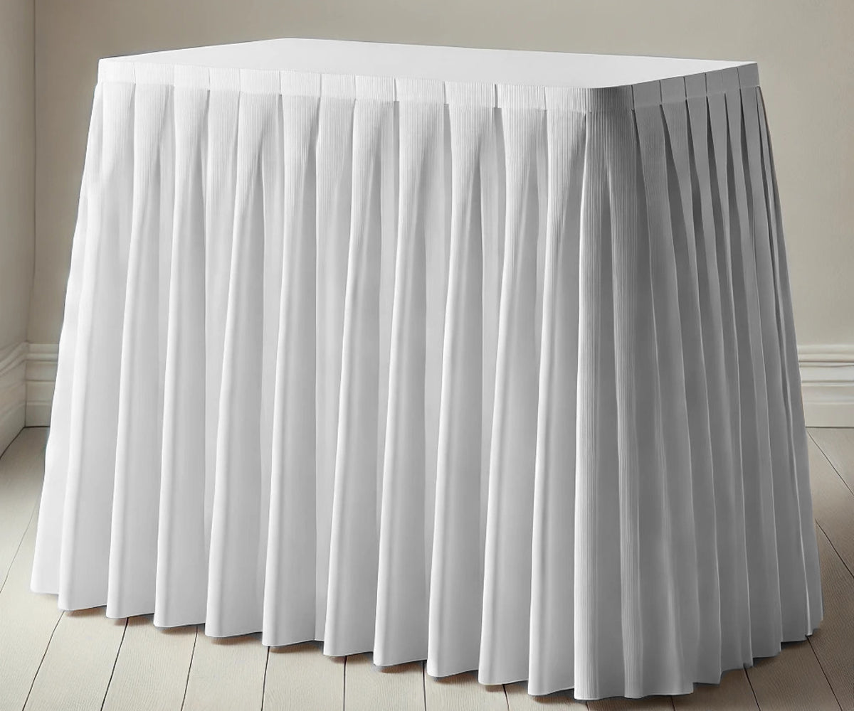 Elegant white cotton table skirt draped around a rectangular table for a wedding setup Elegant white cotton table skirt draped around a rectangular table for a wedding setup
