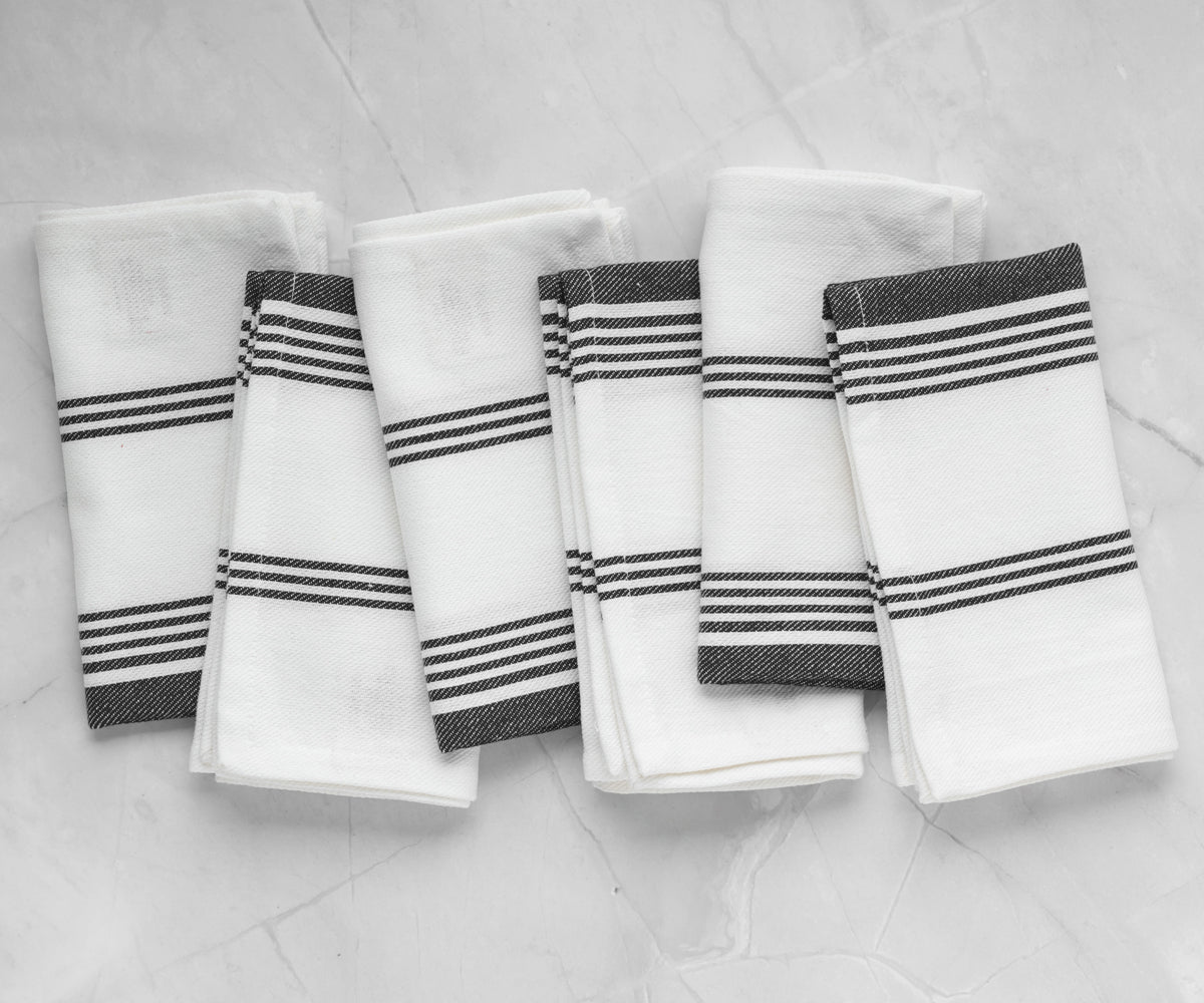 A set of four black striped napkins neatly arranged on a marble countertop A set of four black striped napkins neatly arranged on a marble countertop