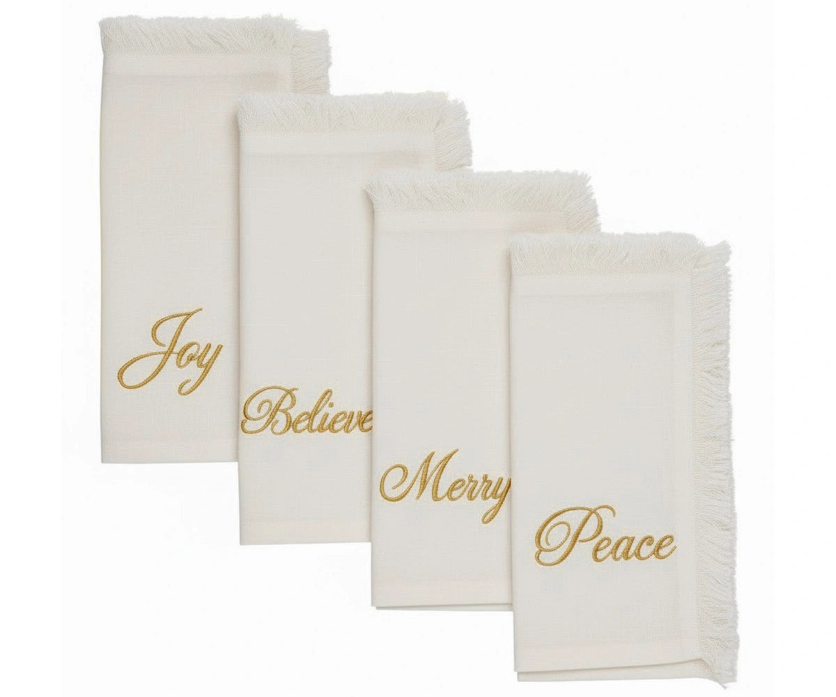 Elegant white embroidered napkins with gold lettering and fringed edges for festive table settings Elegant white embroidered napkins with gold lettering and fringed edges for festive table settings