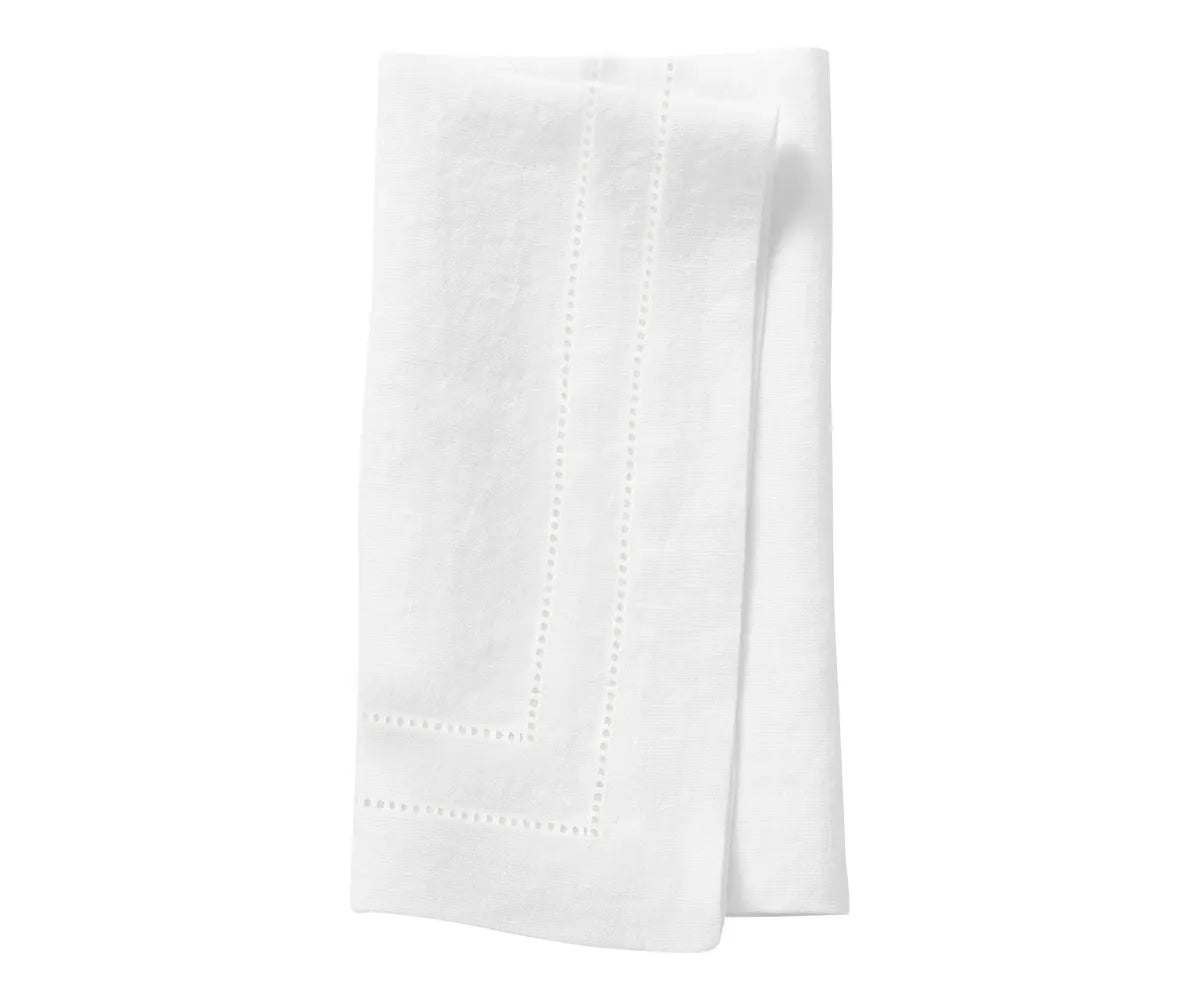 Elegant white linen hemstitch napkins neatly folded on a dinner table setting Elegant white linen hemstitch napkins neatly folded on a dinner table setting