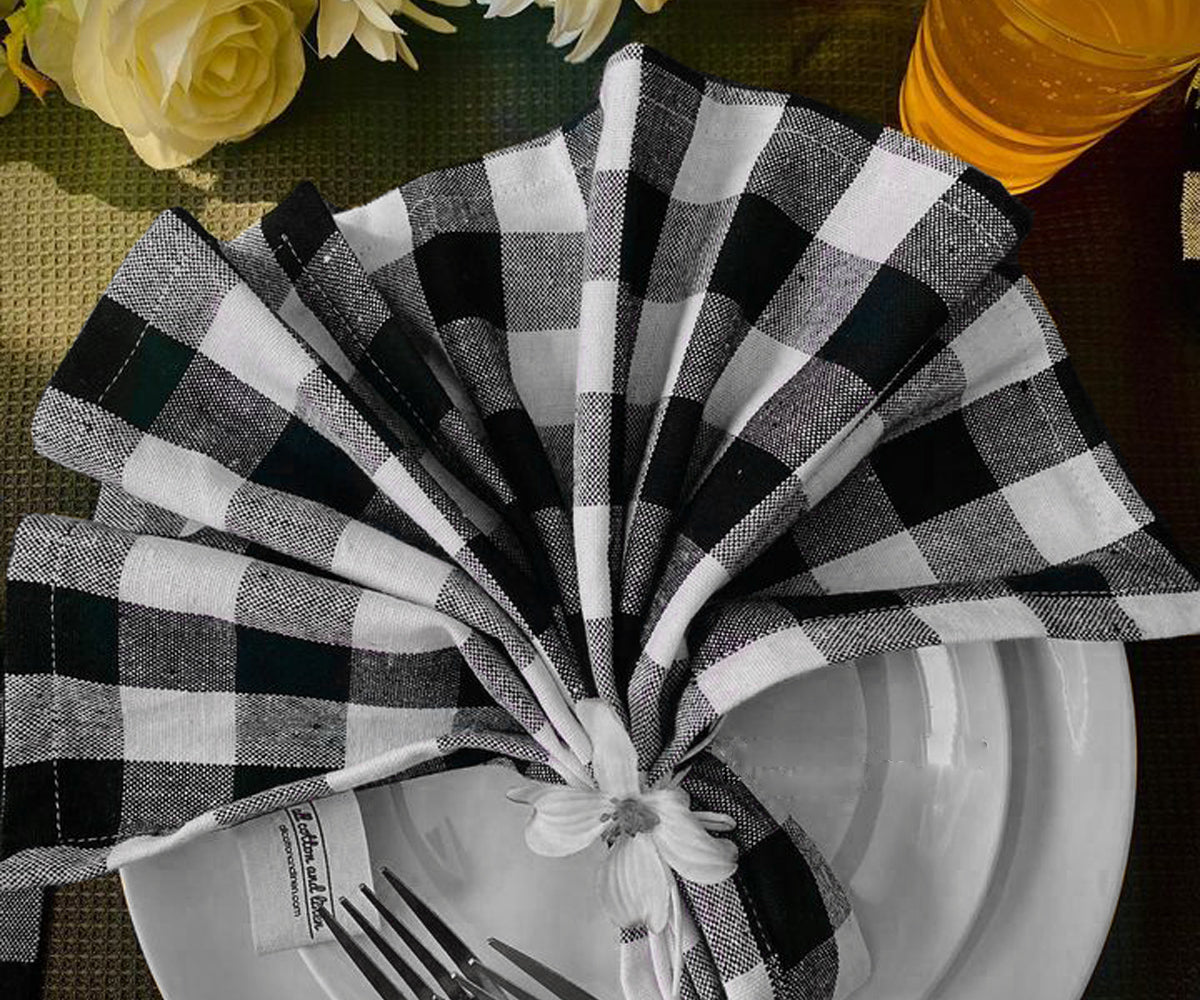 Black and white checkered napkin folded neatly on a white plate with floral decor. Black and white checkered napkin folded neatly on a white plate with floral decor.