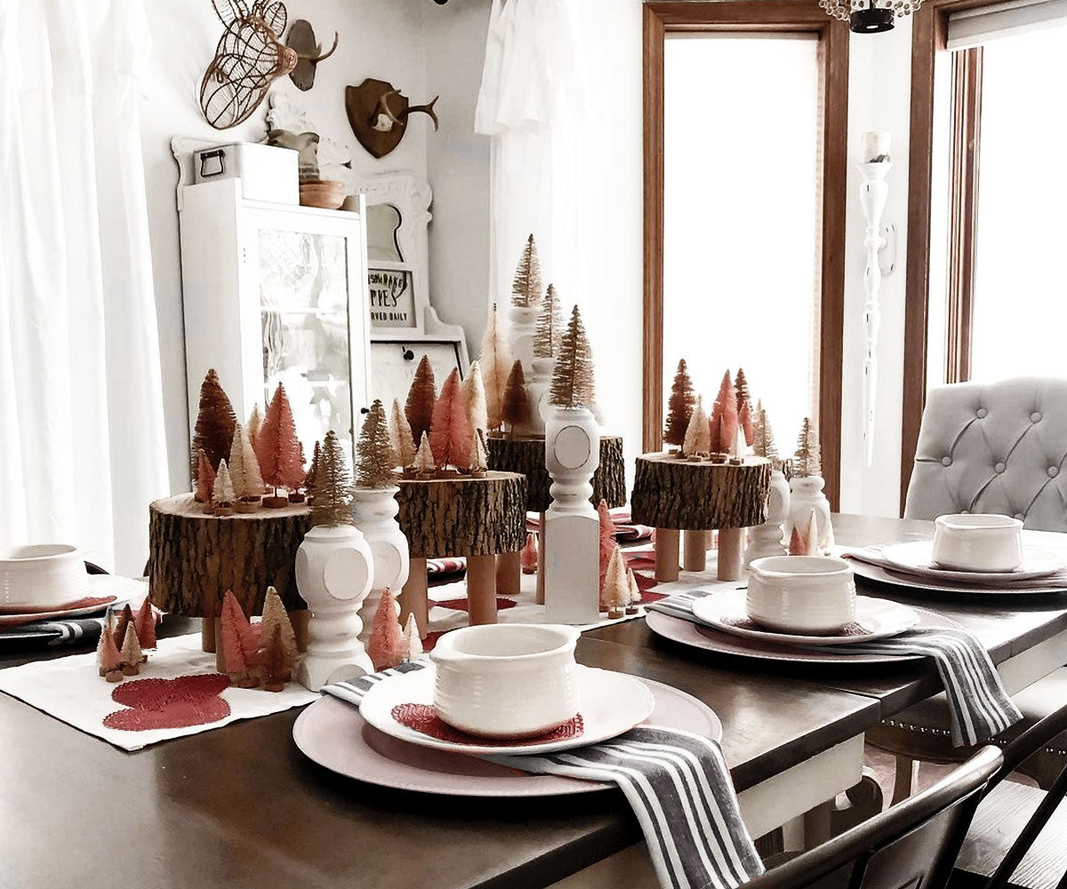 Festive dining room table setting with wooden trees and pink plates. Festive dining room table setting with wooden trees and pink plates.