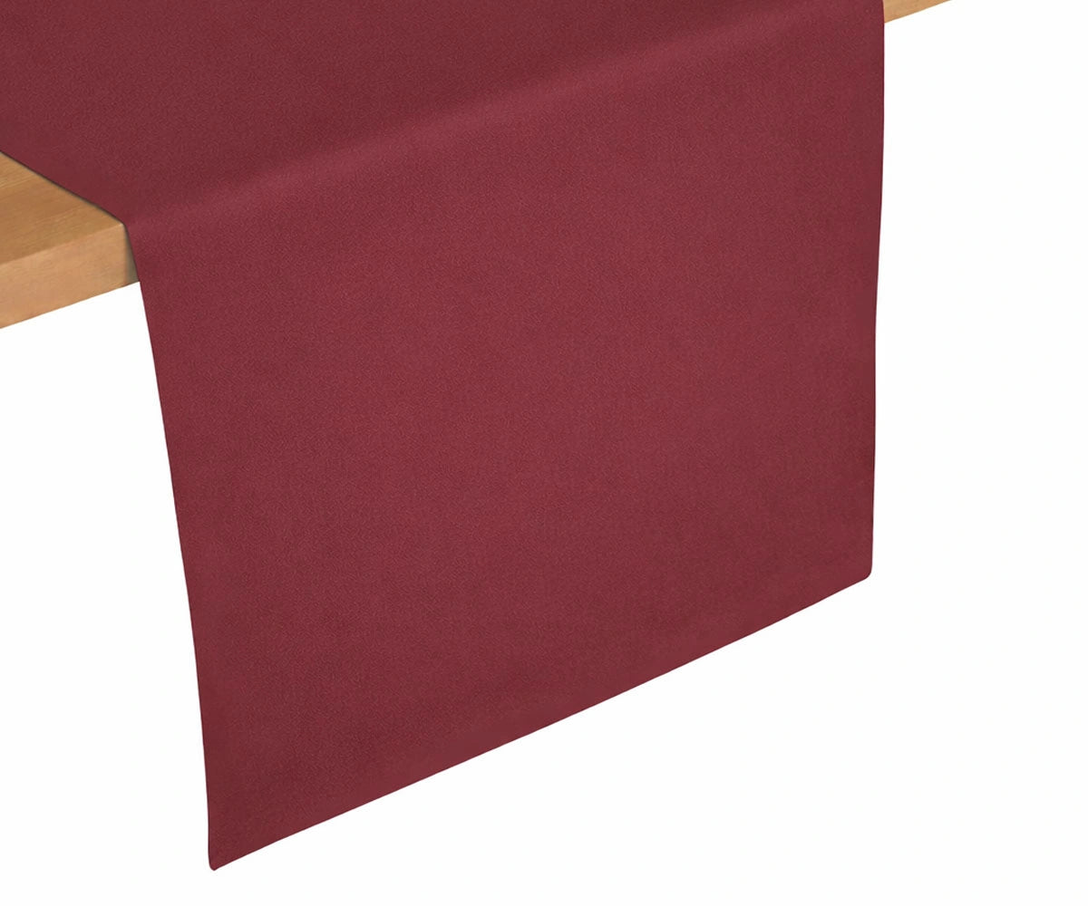 Burgundy cotton table runner draped on wooden table, rich festive color ideal for holidays and special occasions Burgundy cotton table runner draped on wooden table, rich festive color ideal for holidays and special occasions