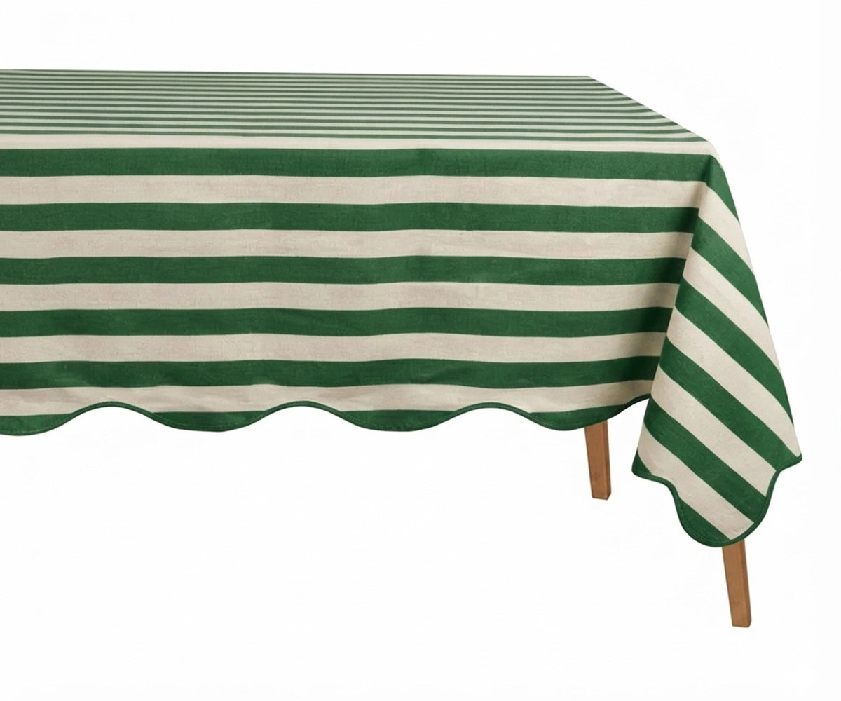 Green and white cabana striped tablecloth with a scalloped edge on a wooden table. Green and white cabana striped tablecloth with a scalloped edge on a wooden table.