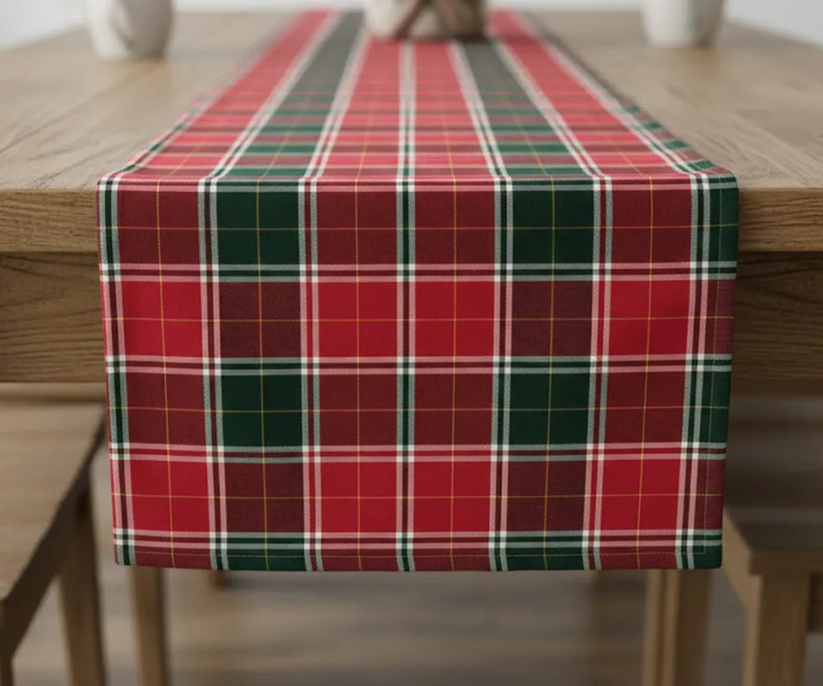 Red, white, and green buffalo plaid cotton table runner laid across a holiday table, adding a warm and festive Christmas farmhouse touch. Red, white, and green buffalo plaid cotton table runner laid across a holiday table, adding a warm and festive Christmas farmhouse touch.