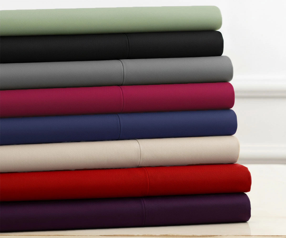 Stack of folded cotton bedsheets in assorted solid colors Stack of folded cotton bedsheets in assorted solid colors