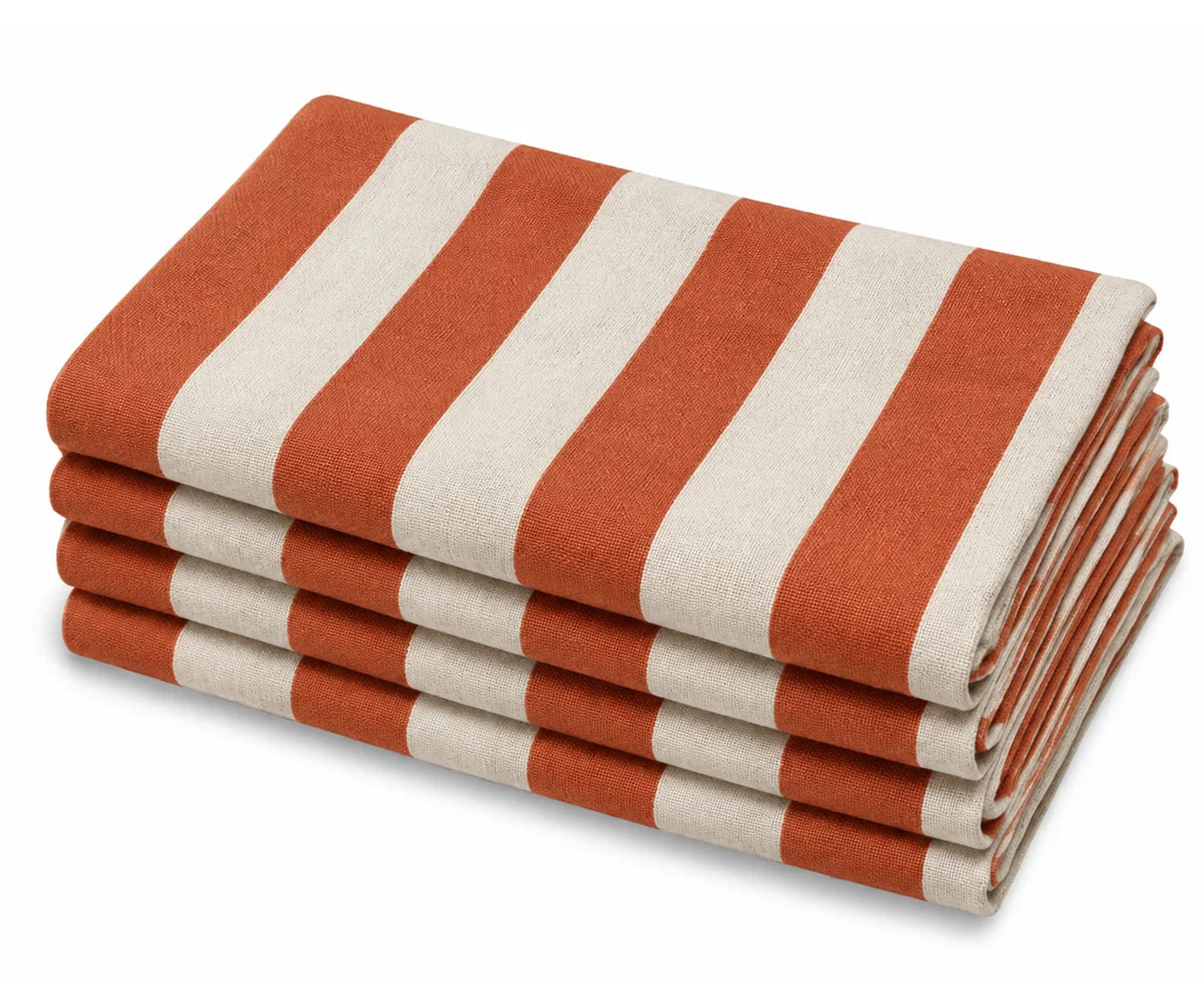 Set of folded cotton cabana stripe dinner napkins in terracotta orange and white, neatly stacked against a plain white background. Set of folded cotton cabana stripe dinner napkins in terracotta orange and white, neatly stacked against a plain white background.