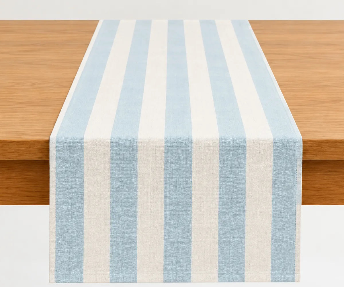 A light blue and off-white striped table runner draped over a wooden table. A light blue and off-white striped table runner draped over a wooden table.