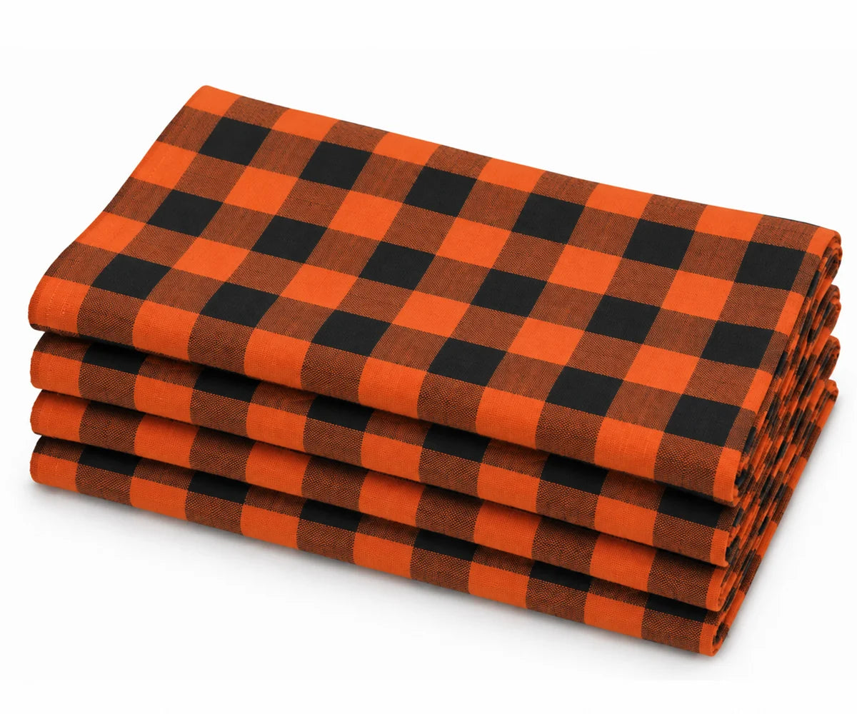 Folded stack of orange and black buffalo plaid cotton dinner napkins against a white background. Folded stack of orange and black buffalo plaid cotton dinner napkins against a white background.