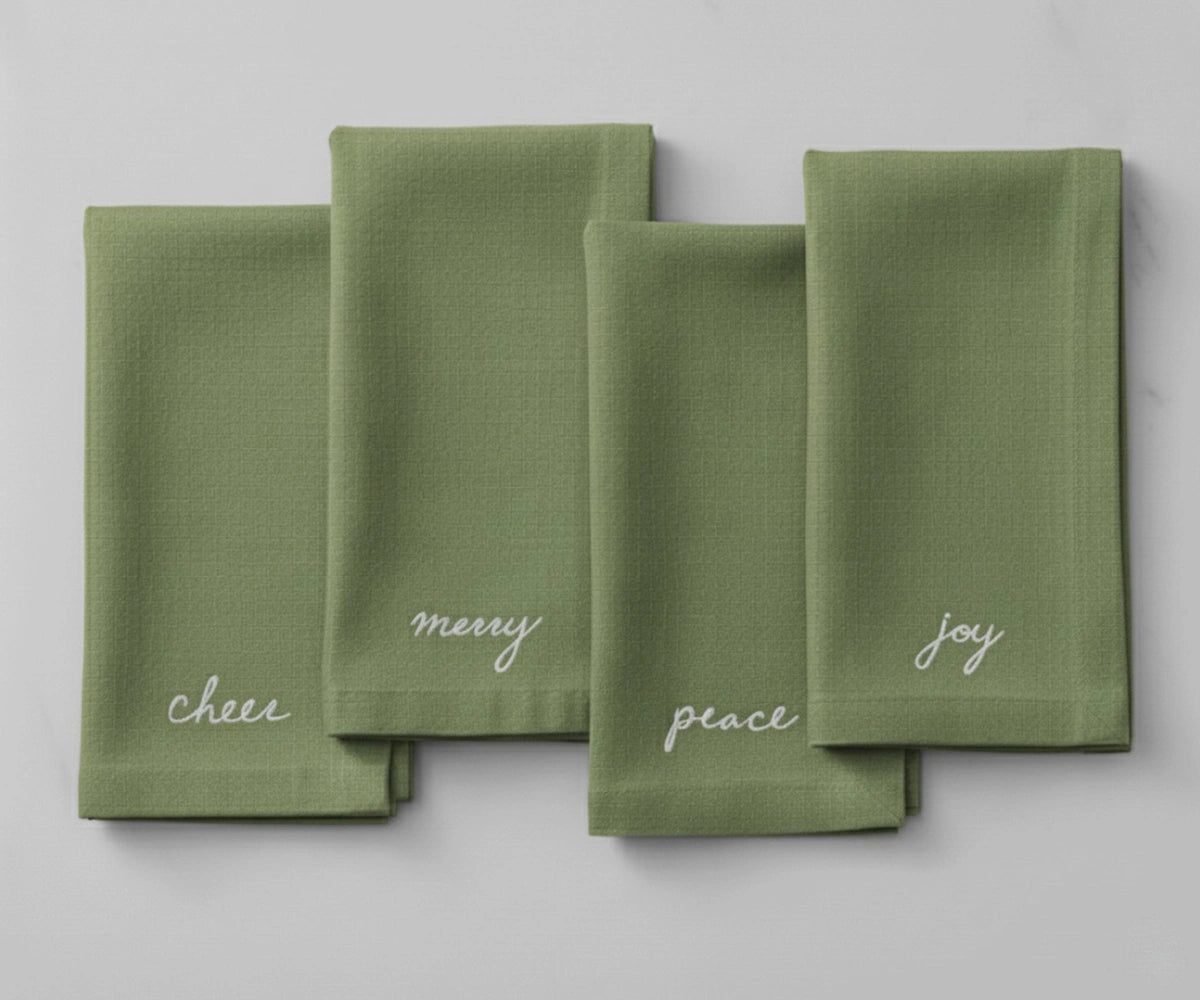 Sage green Christmas embroidered napkin with white holiday sentiment embroidery — Peace, Joy, Merry, and Cheer. Sage green Christmas embroidered napkin with white holiday sentiment embroidery — Peace, Joy, Merry, and Cheer.