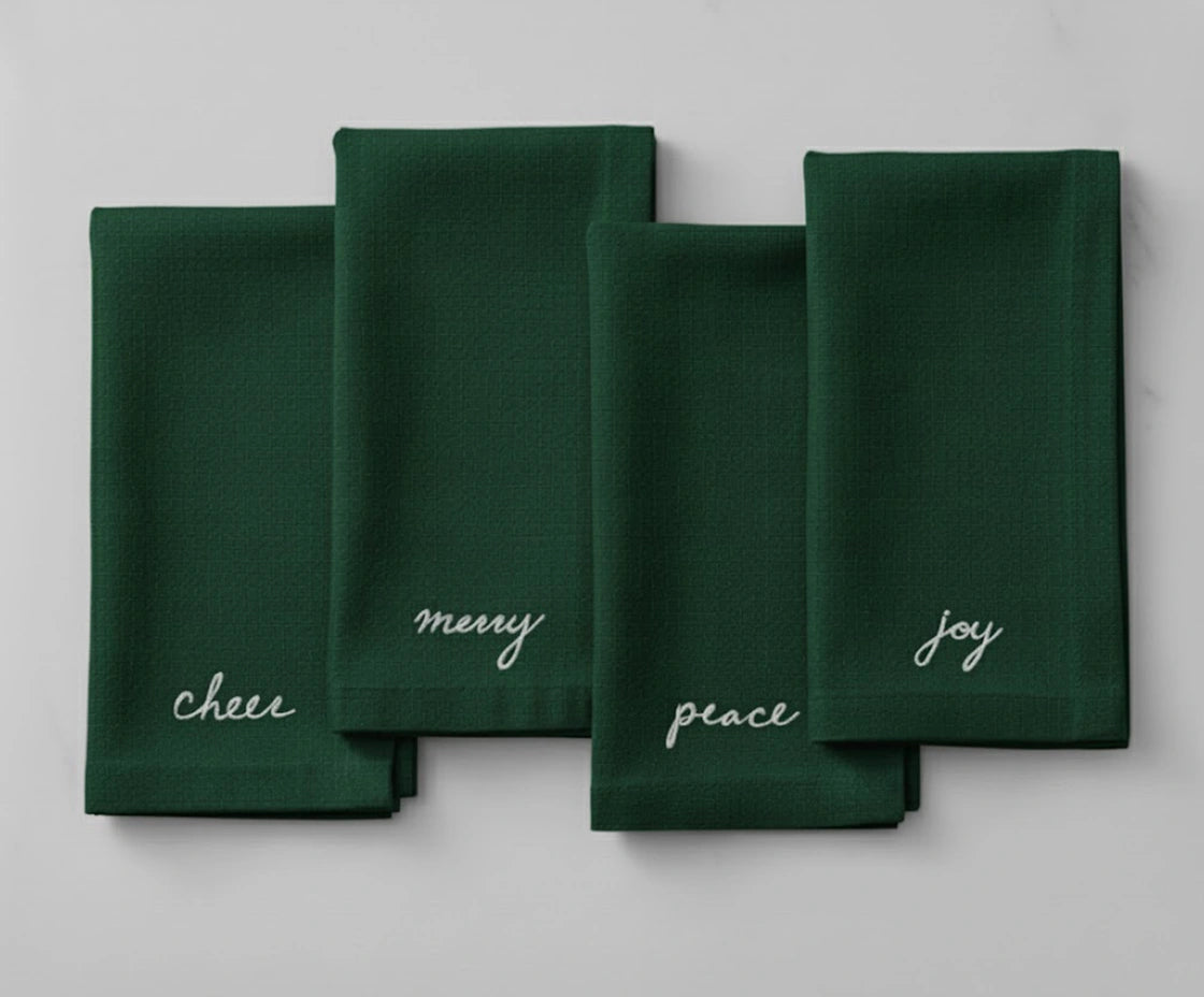 Green Christmas embroidered napkin with white holiday sentiment embroidery — Peace, Joy, Merry, and Cheer. Green Christmas embroidered napkin with white holiday sentiment embroidery — Peace, Joy, Merry, and Cheer.