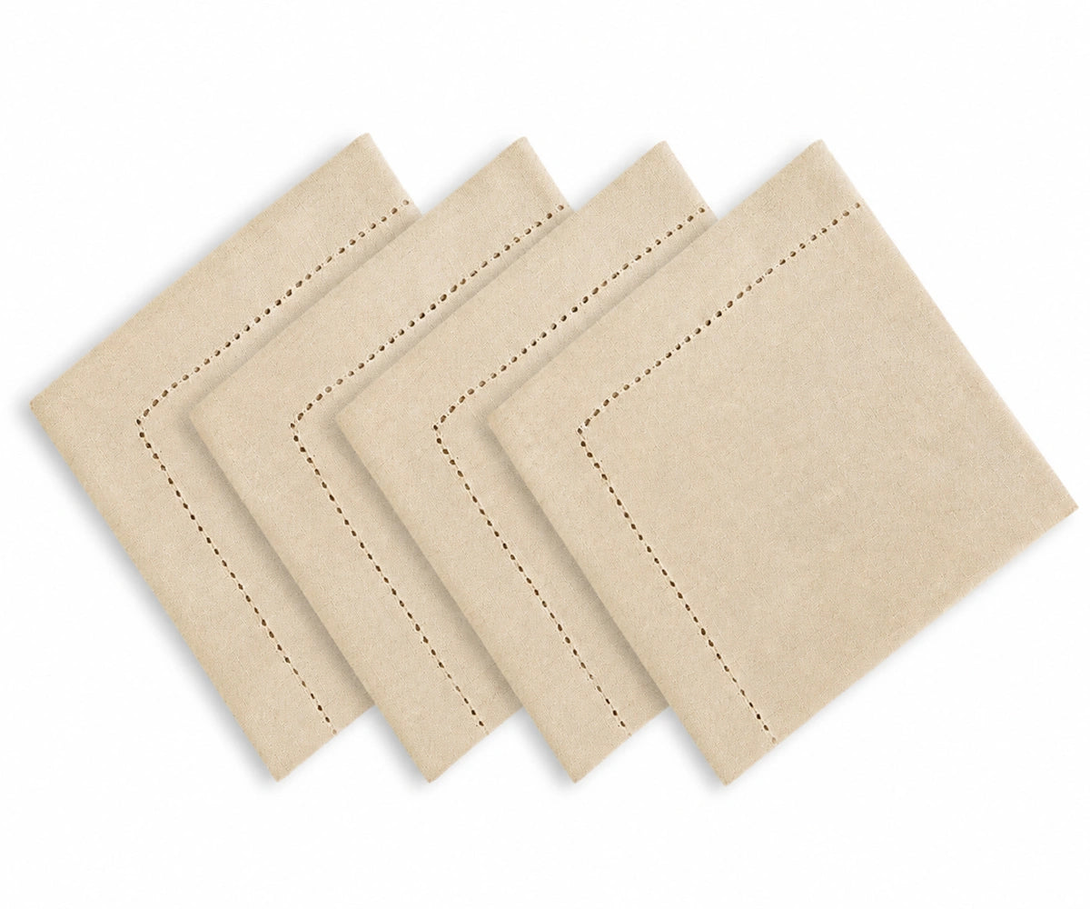 Four square beige napkins with decorative dashed border stitching, arranged in a staggered fan layout on a white background. Four square beige napkins with decorative dashed border stitching, arranged in a staggered fan layout on a white background.