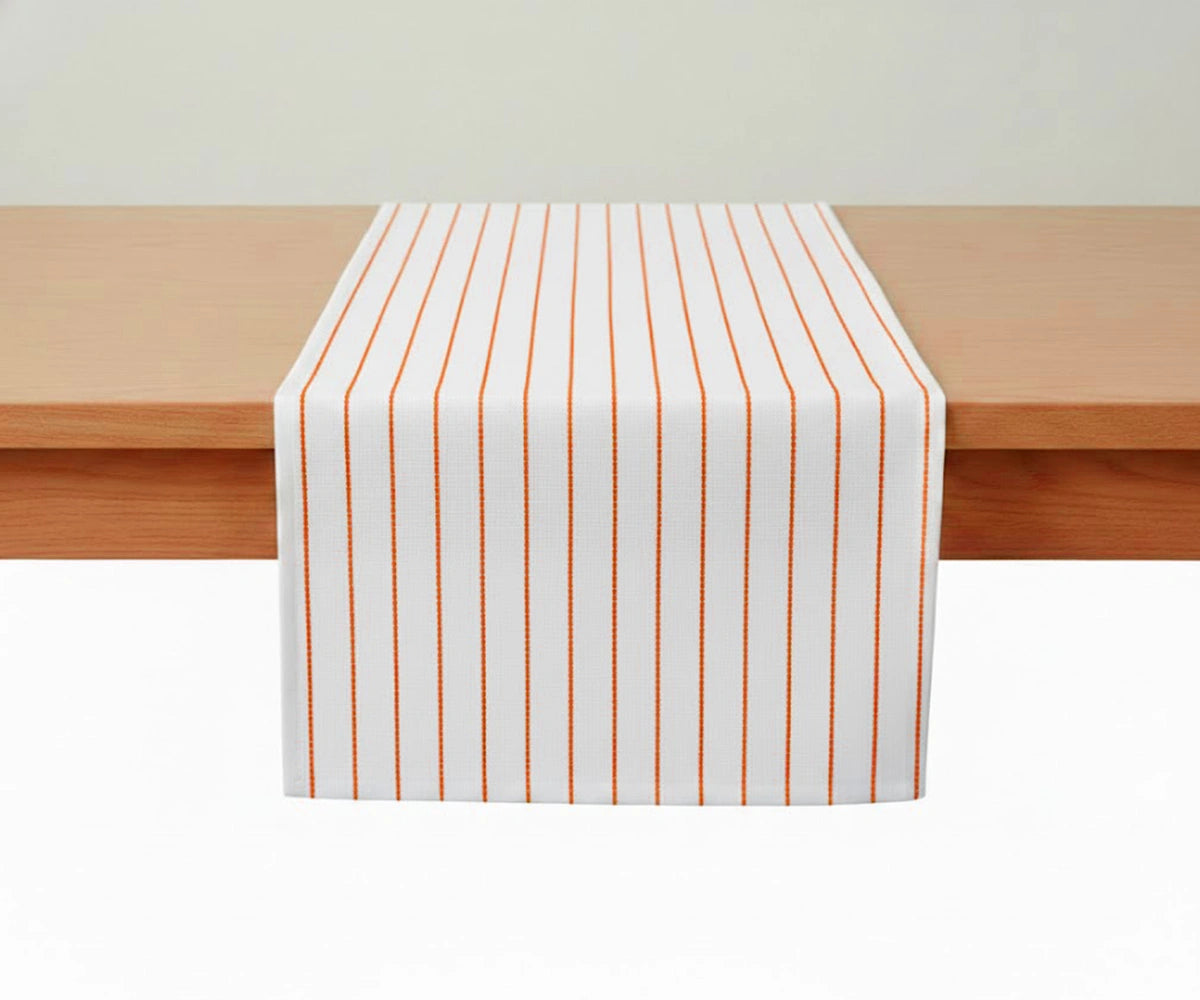 Orange striped cotton table runner on a wooden dining table Orange striped cotton table runner on a wooden dining table