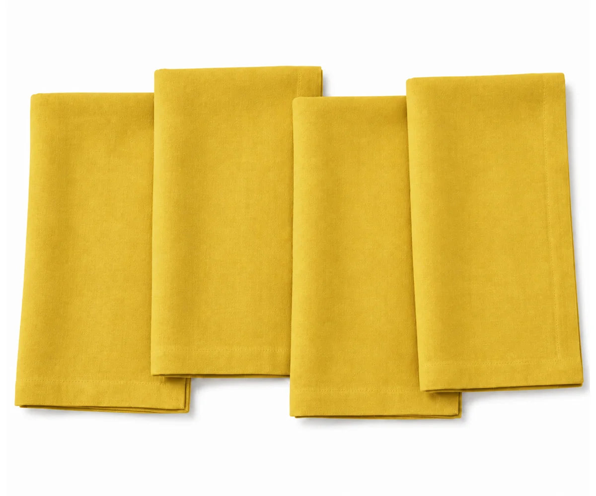 Set of four folded sunflower yellow cotton dinner napkins arranged on a white background. Set of four folded sunflower yellow cotton dinner napkins arranged on a white background.