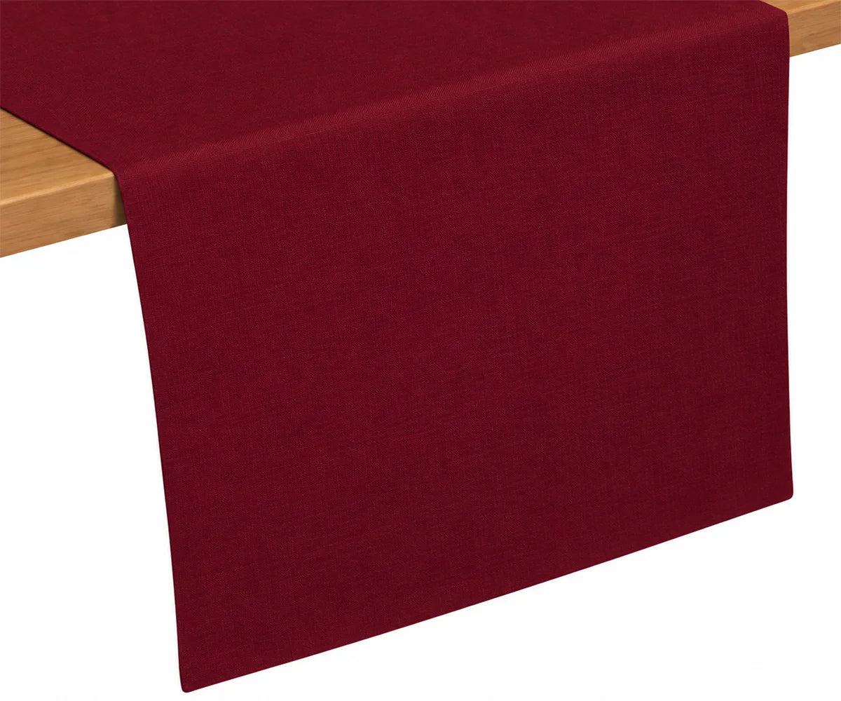 Burgundy cotton table runner draped on wooden table, rich festive color ideal for holidays and special occasions Burgundy cotton table runner draped on wooden table, rich festive color ideal for holidays and special occasions