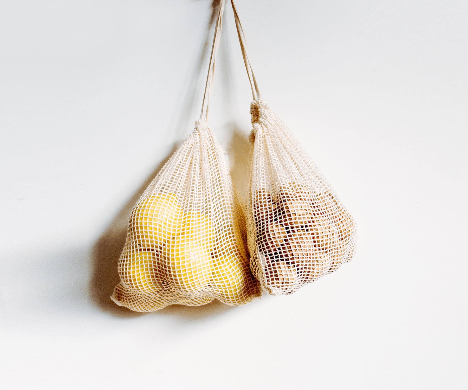 Multiple reusable mesh produce bags filled with a mix of fruits and vegetables