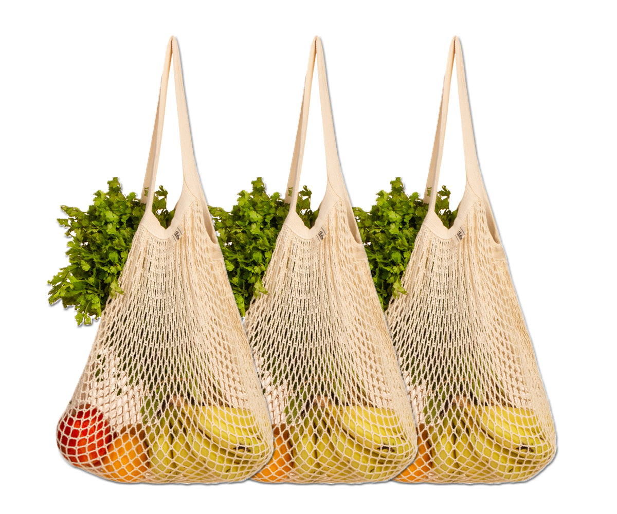 Assorted fruits and vegetables peeking from three cotton string bags Assorted fruits and vegetables peeking from three cotton string bags