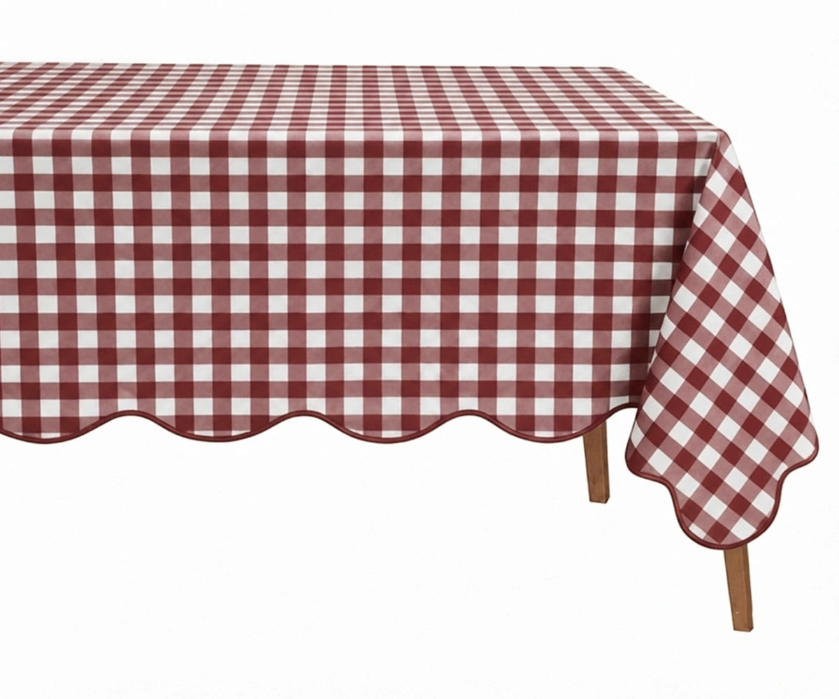Dark red and white checkered cotton tablecloth with a decorative scalloped edge draped over a table Dark red and white checkered cotton tablecloth with a decorative scalloped edge draped over a table