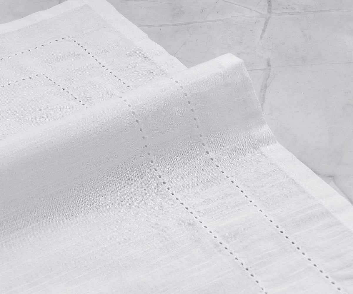 Set of 12 hemstitched cloth napkins displayed on a dining table Set of 12 hemstitched cloth napkins displayed on a dining table
