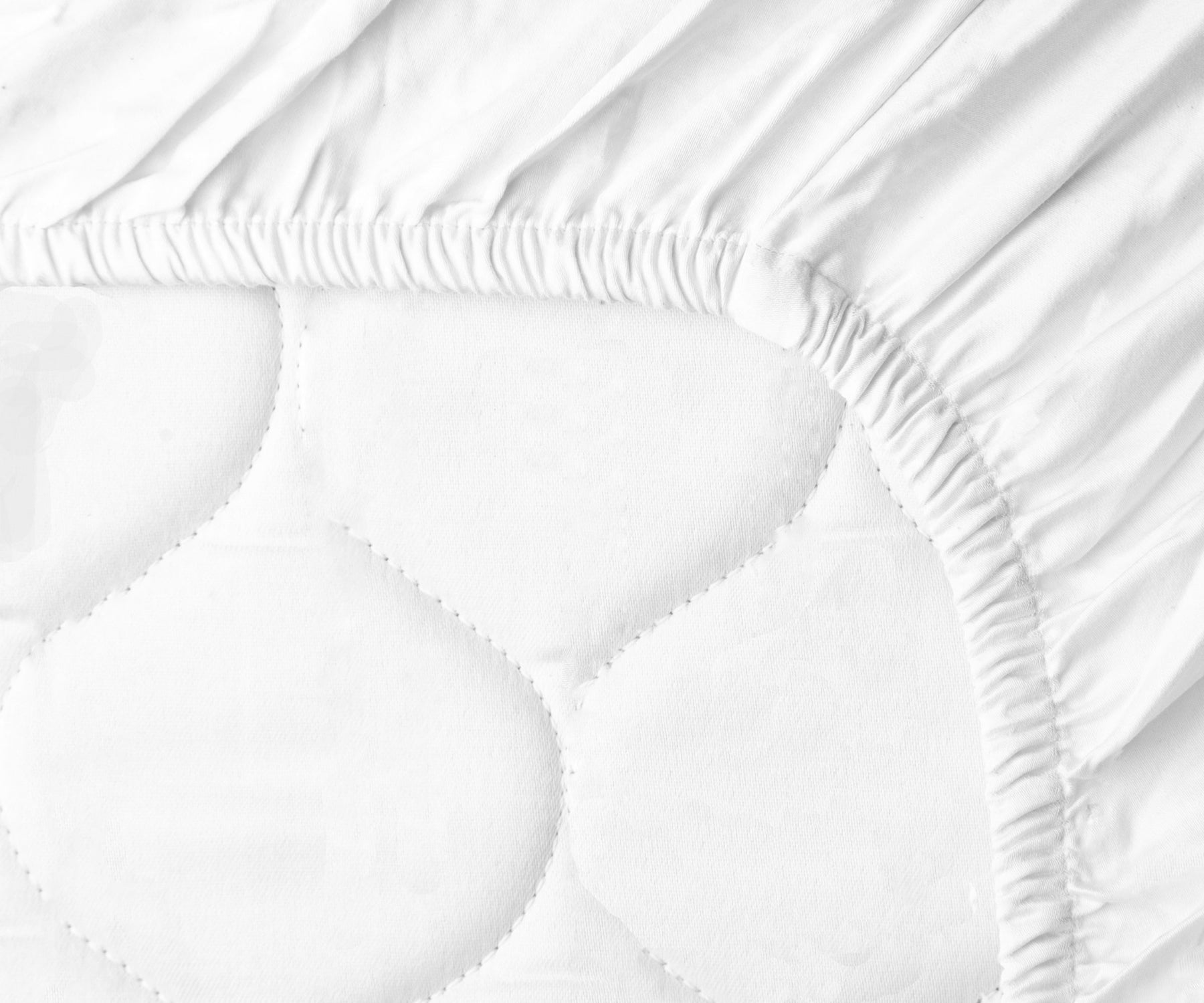Close up view of a mattress covered with a white cotton fitted sheet