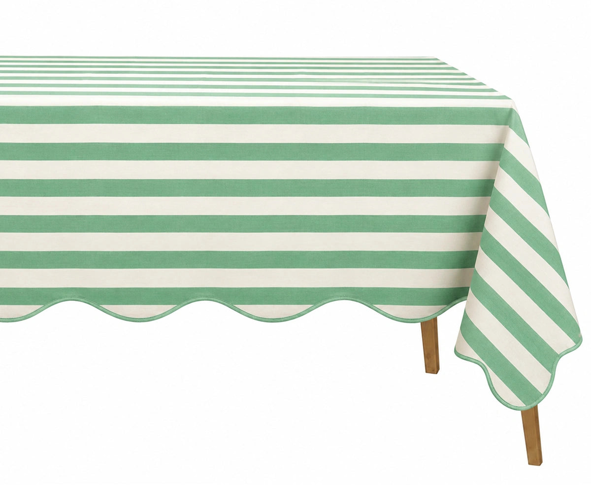 Green and white cabana striped tablecloth with a scalloped edge on a wooden table. Green and white cabana striped tablecloth with a scalloped edge on a wooden table.
