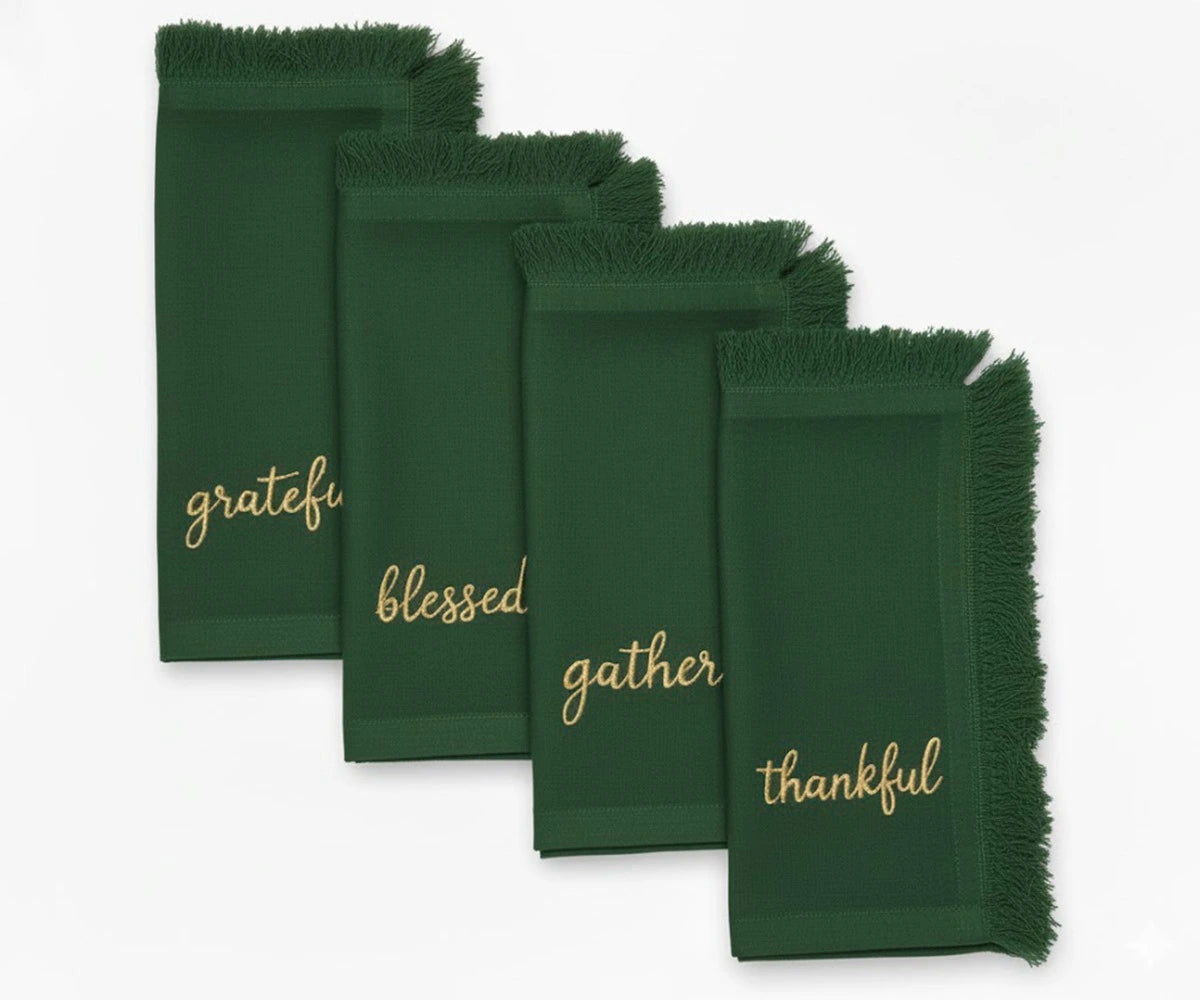 Elegant green embroidered napkins with gold lettering and fringed edges for festive table settings Elegant green embroidered napkins with gold lettering and fringed edges for festive table settings