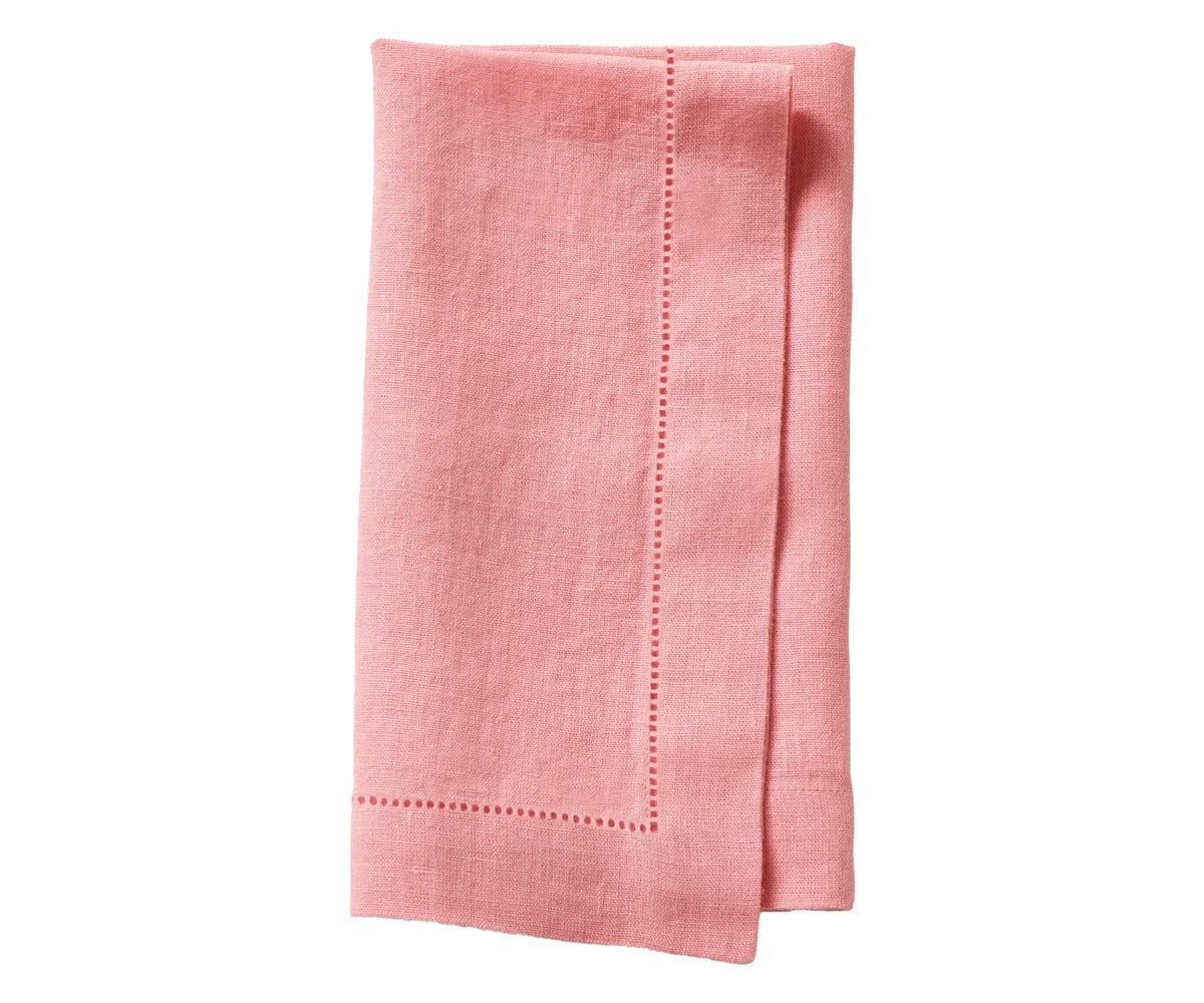 Set of hemstitch linen napkins in soft neutral tones, neatly folded on a dining table. Set of hemstitch linen napkins in soft neutral tones, neatly folded on a dining table.