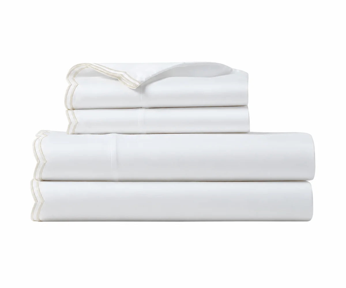 Folded white cotton sheet set with ivory scalloped embroidered trim. Folded white cotton sheet set with ivory scalloped embroidered trim.