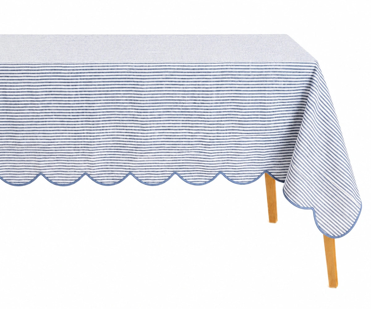 Light blue and white thin striped linen tablecloth with a decorative light blue scalloped edge draped over a table. Light blue and white thin striped linen tablecloth with a decorative light blue scalloped edge draped over a table.
