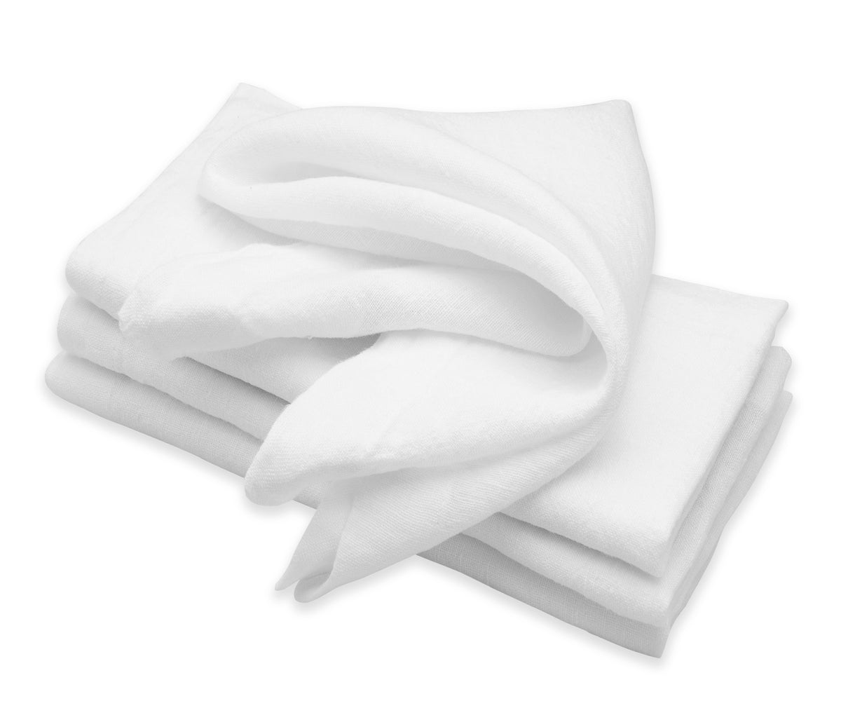 Stack of white linen napkins presented on a white tabletop Stack of white linen napkins presented on a white tabletop