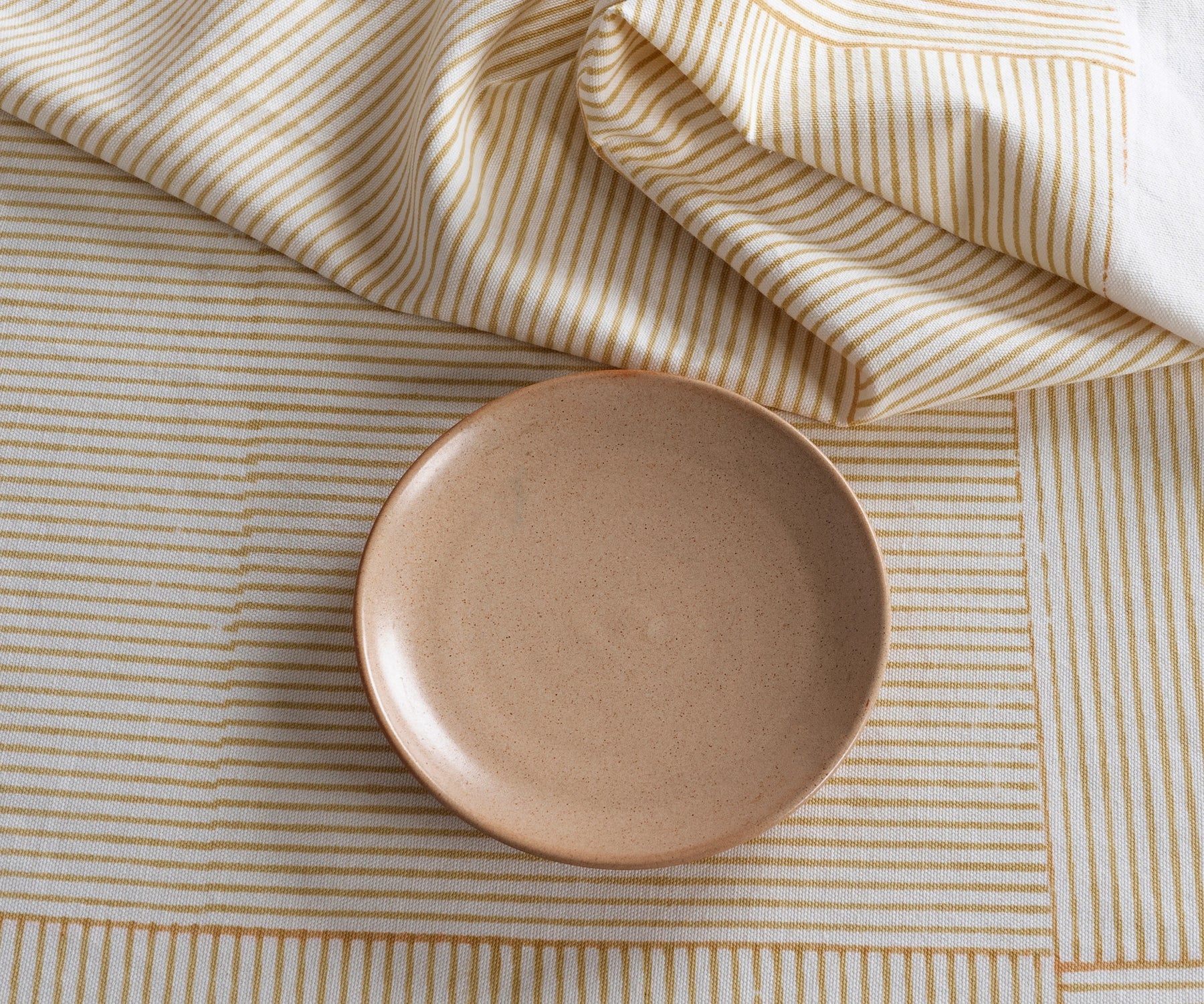Beige block print tablecloth with neutral dinnerware and floral centerpiece Beige block print tablecloth with neutral dinnerware and floral centerpiece