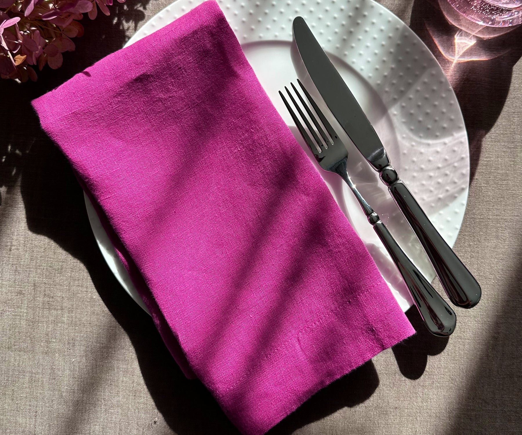 Dinner setting with an orchid plain linen napkin on a plate and sage leaves for detail. Dinner setting with an orchid plain linen napkin on a plate and sage leaves for detail.