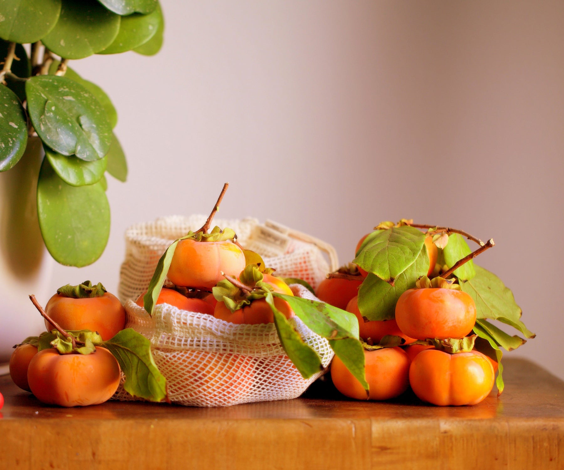 Fresh oranges spilling out of a cotton string bag on a wooden surface Fresh oranges spilling out of a cotton string bag on a wooden surface