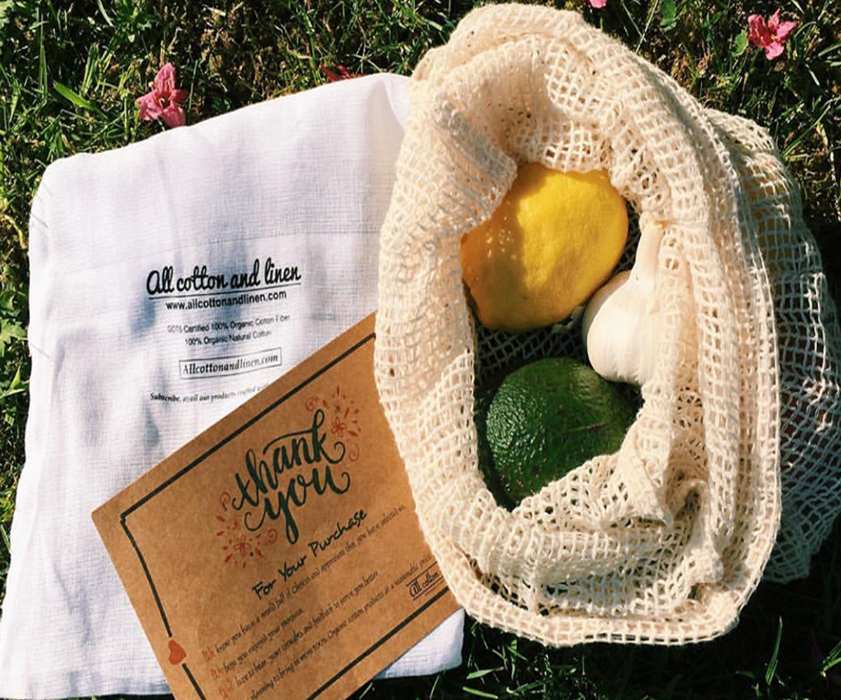 "A set of reusable produce bags in various sizes next to a grocery basket."