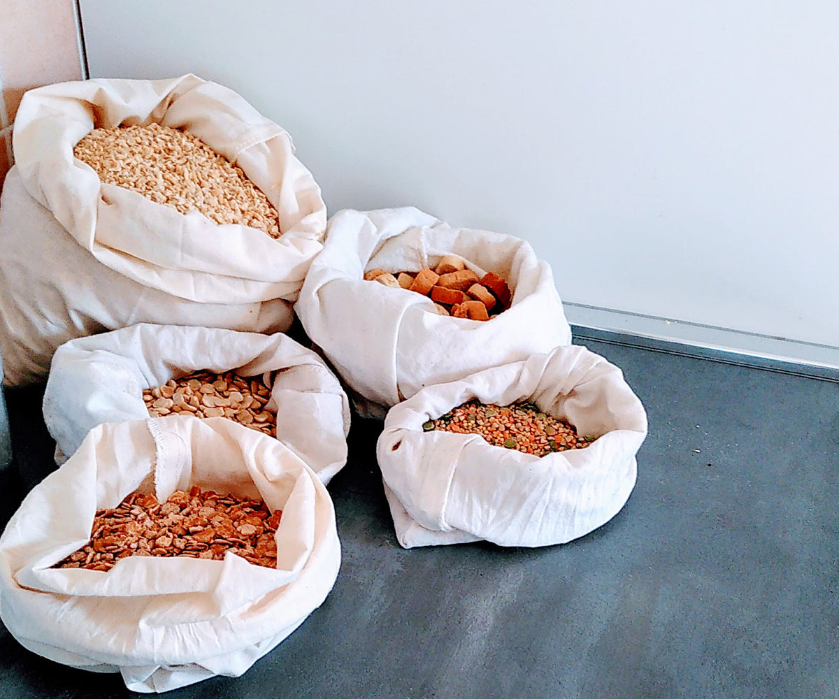 White muslin bags containing dried foods like grains and seeds on a countertop. White muslin bags containing dried foods like grains and seeds on a countertop.