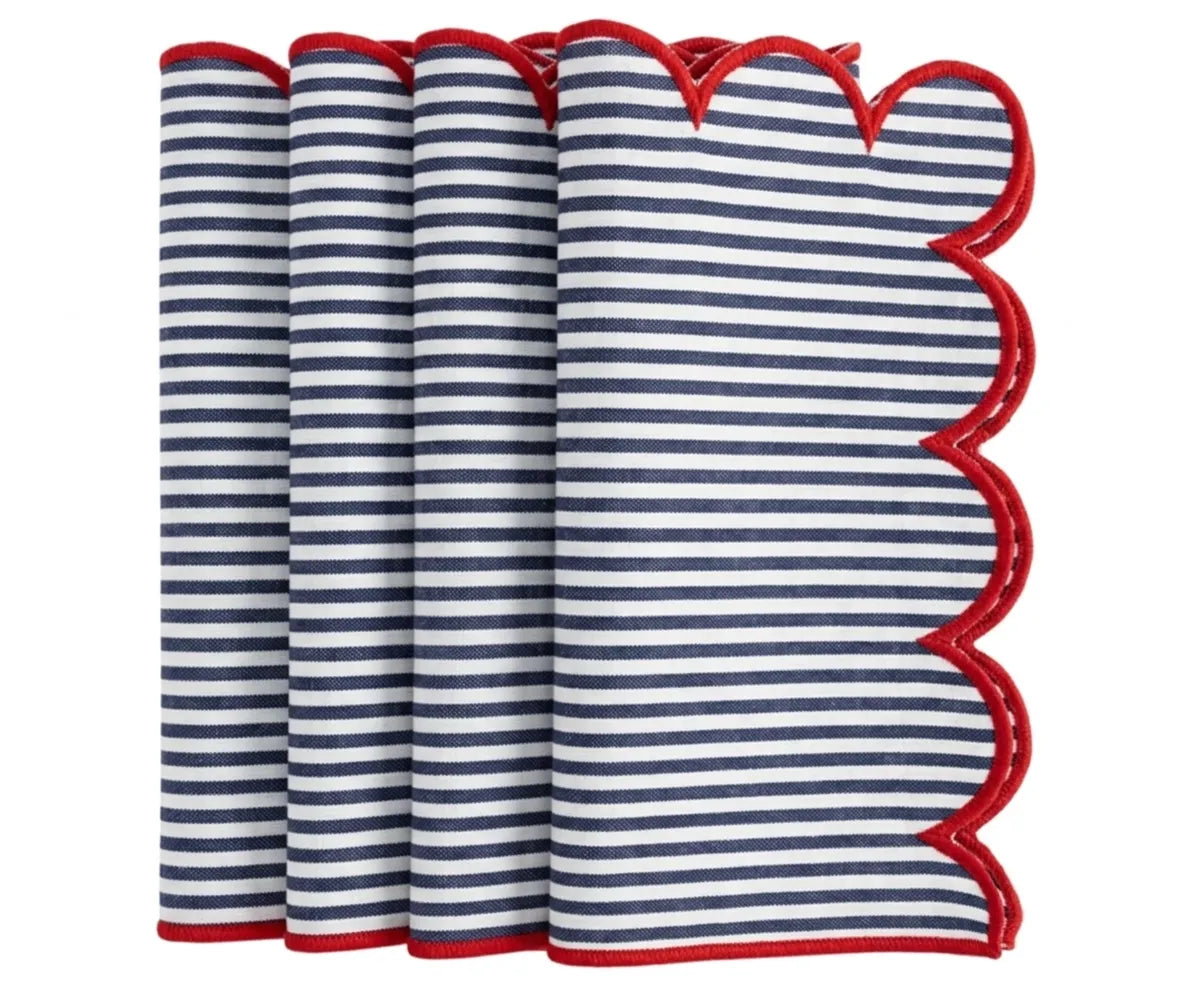 Navy and white striped cloth napkin finished with a contrasting red scalloped trim, neatly folded for table presentation. Navy and white striped cloth napkin finished with a contrasting red scalloped trim, neatly folded for table presentation.