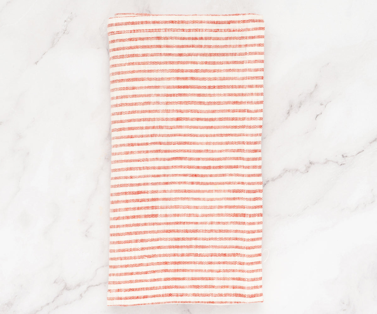 Stack of red and white striped linen napkins neatly folded on a wooden table Stack of red and white striped linen napkins neatly folded on a wooden table