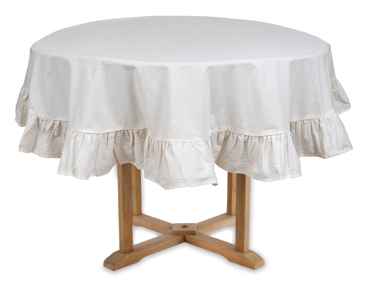 Ruffled round cotton tablecloth in natural color on a rustic wooden table Ruffled round cotton tablecloth in natural color on a rustic wooden table