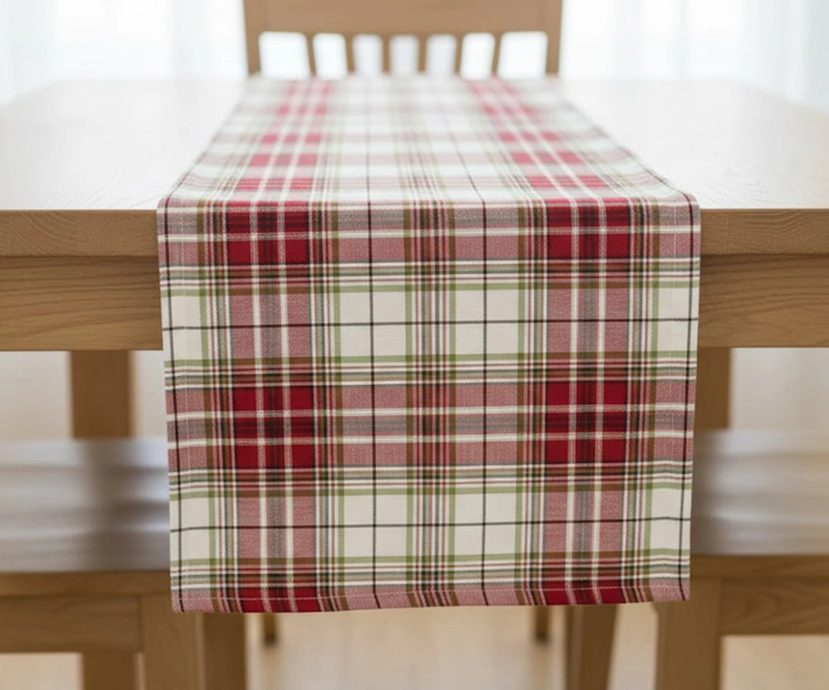 Red tartan plaid cotton table runner with green, white, and black checks adding festive charm and classic elegance to a Christmas dining table. Red tartan plaid cotton table runner with green, white, and black checks adding festive charm and classic elegance to a Christmas dining table.