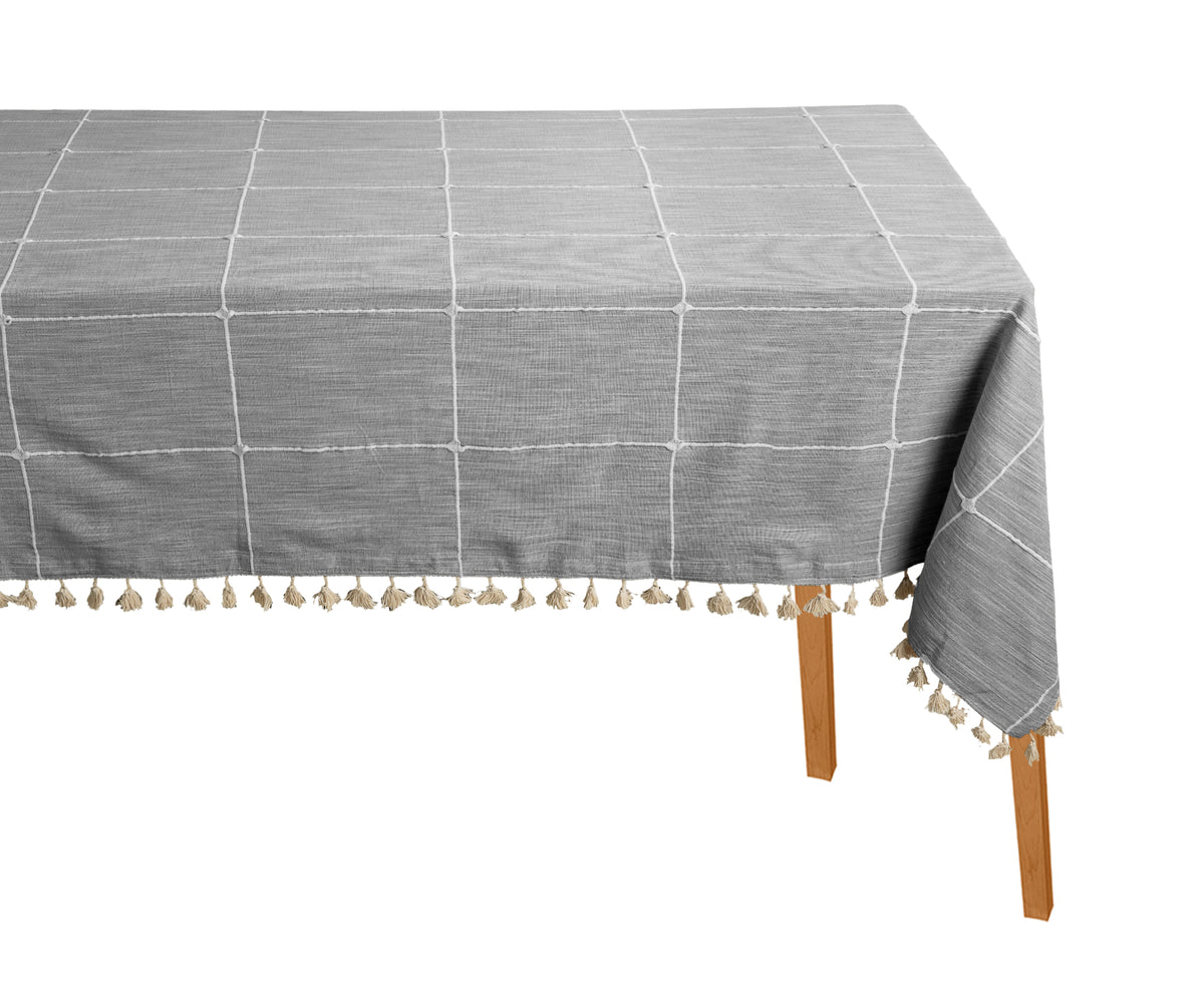 Gray checkered tablecloth with tassels on a wooden table against a white background Gray checkered tablecloth with tassels on a wooden table against a white background