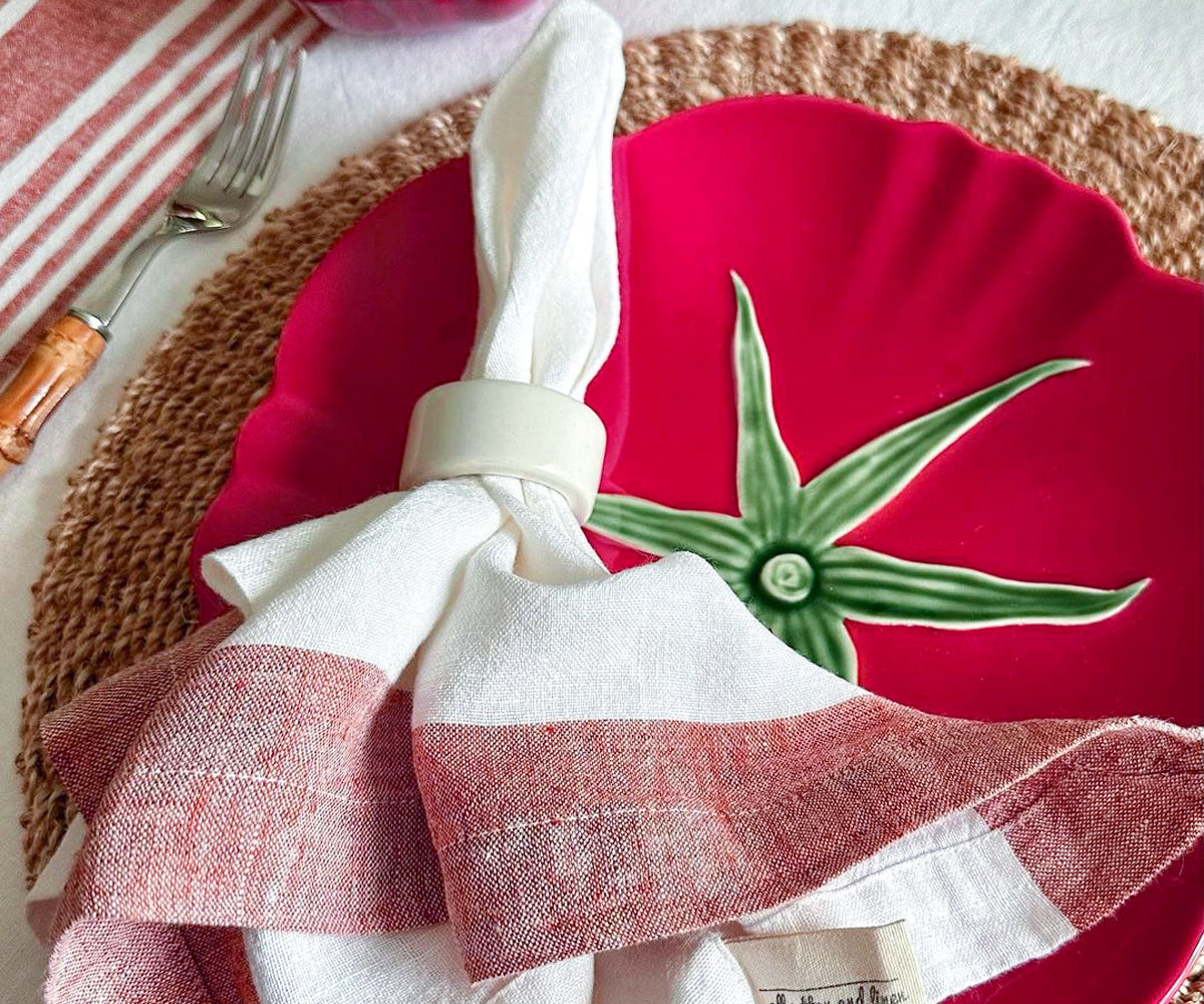 Festive table setting featuring a white linen napkin on a red plate Festive table setting featuring a white linen napkin on a red plate
