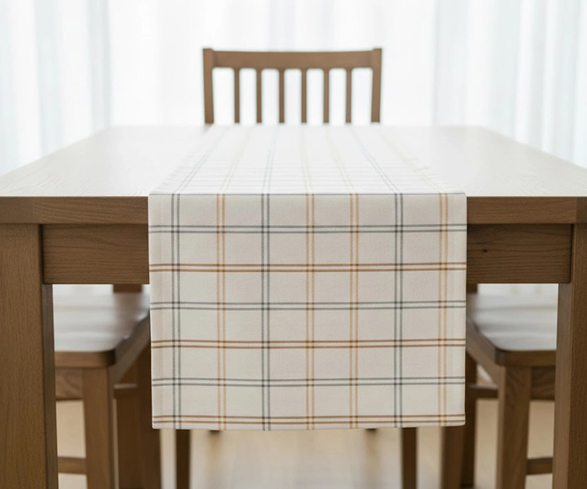 White buffalo plaid cotton table runner with light orange and gray lines adding cozy elegance and festive charm to a modern farmhouse dining table. White buffalo plaid cotton table runner with light orange and gray lines adding cozy elegance and festive charm to a modern farmhouse dining table.