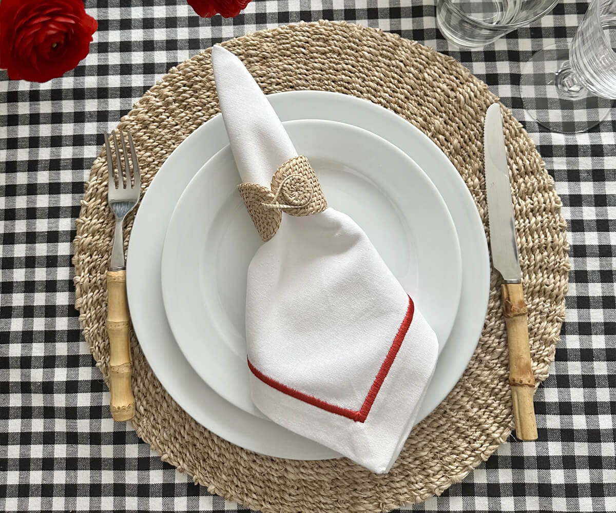 Place setting with a white dinner napkin, red accents and roses