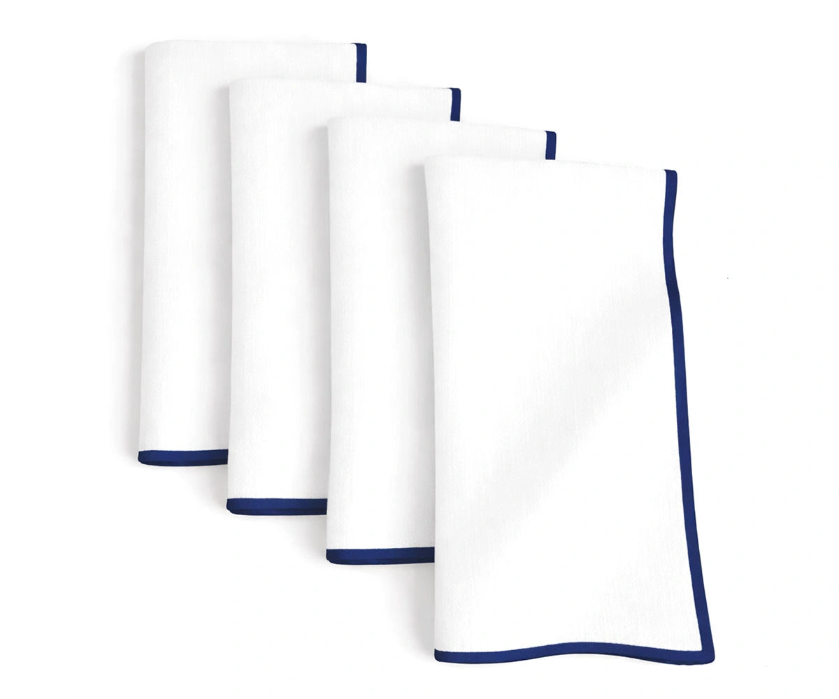 Elegant white base cotton napkins accented with navy merrow stitching for timeless table settings Elegant white base cotton napkins accented with navy merrow stitching for timeless table settings