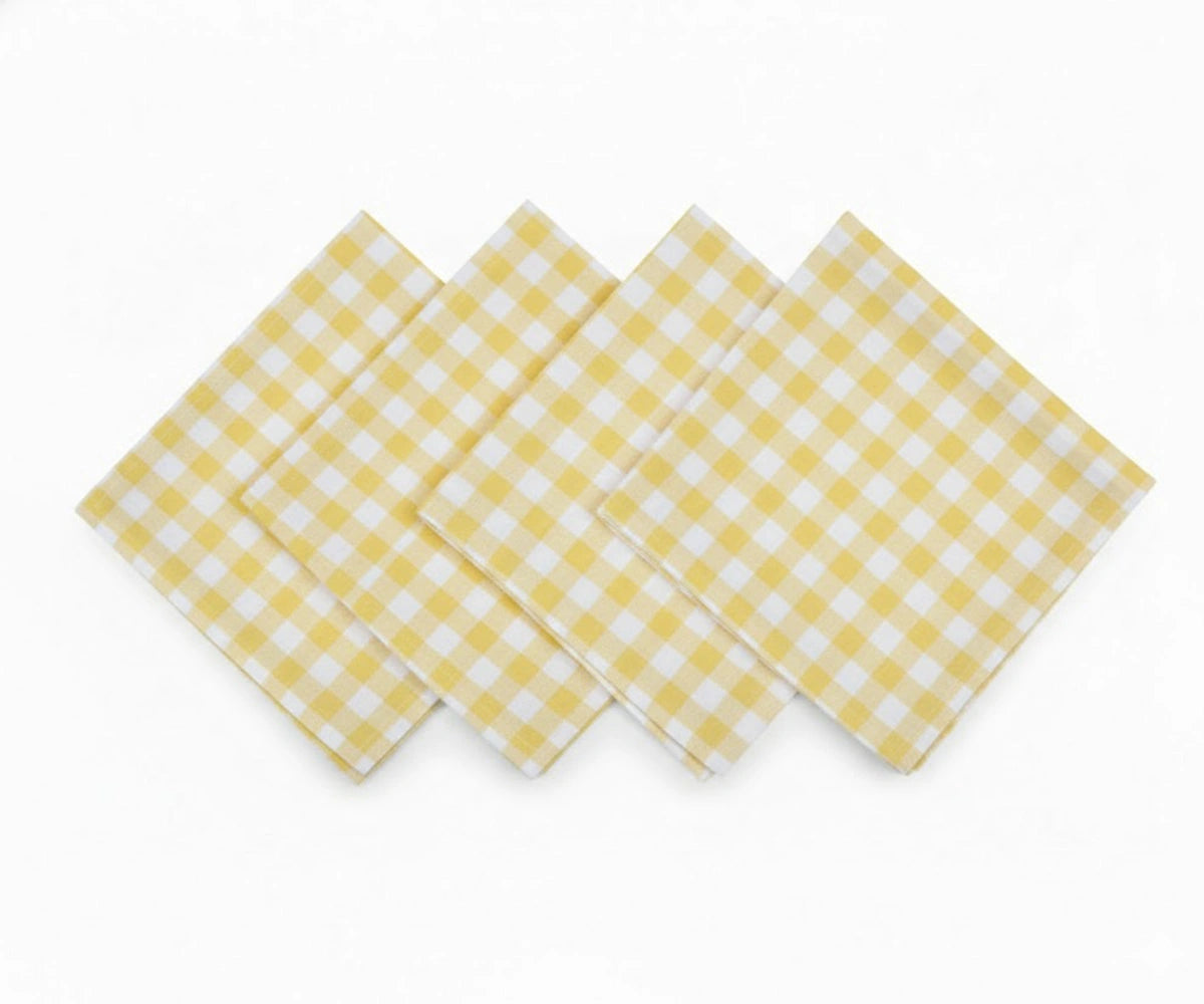 Set of yellow and white checkered cotton napkins laid flat Set of yellow and white checkered cotton napkins laid flat