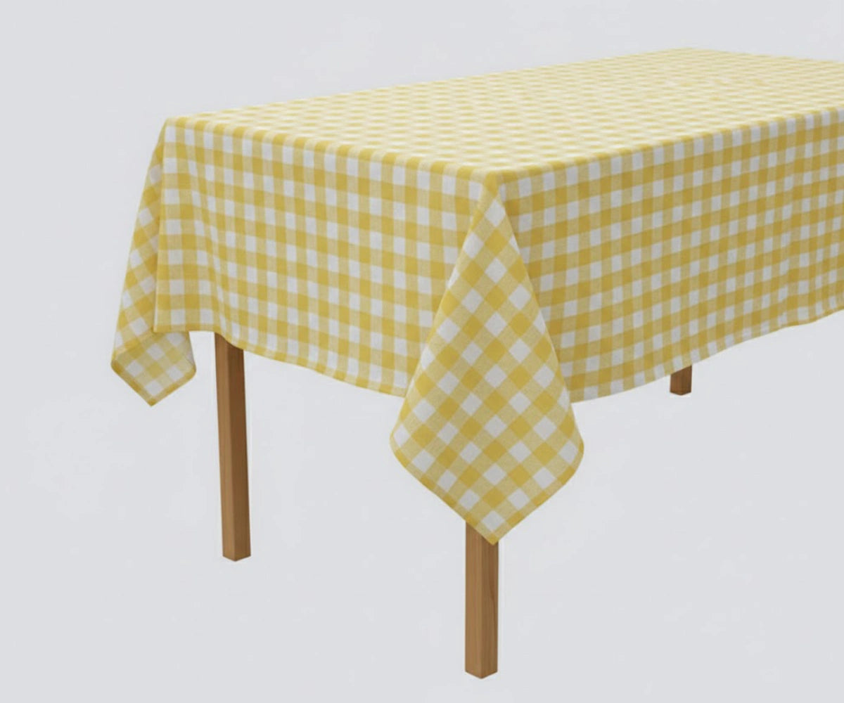 Yellow checked tablecloth styled with white dinnerware and natural woven placemats. Rectangular cotton gingham tablecloth for farmhouse kitchen décor. Yellow checked tablecloth styled with white dinnerware and natural woven placemats. Rectangular cotton gingham tablecloth for farmhouse kitchen décor.