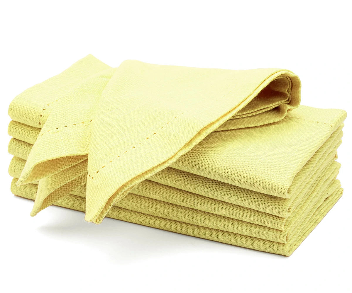 Butter yellow cotton dinner napkins neatly folded on a dining table Butter yellow cotton dinner napkins neatly folded on a dining table