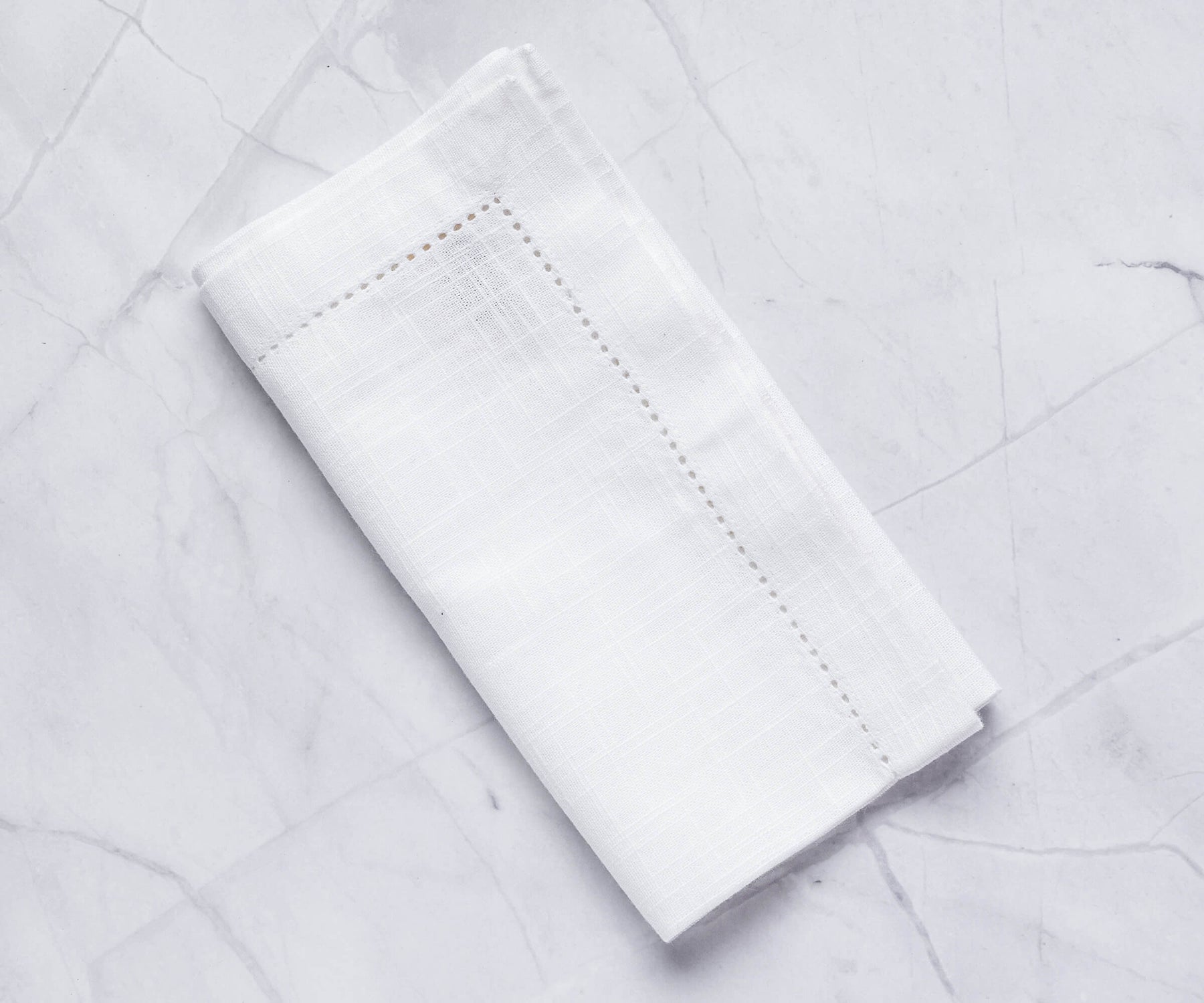 white napkins with 1 white napkins with 1" borders are folded and hemstitched pattern white linen napkins are placed on the white surface