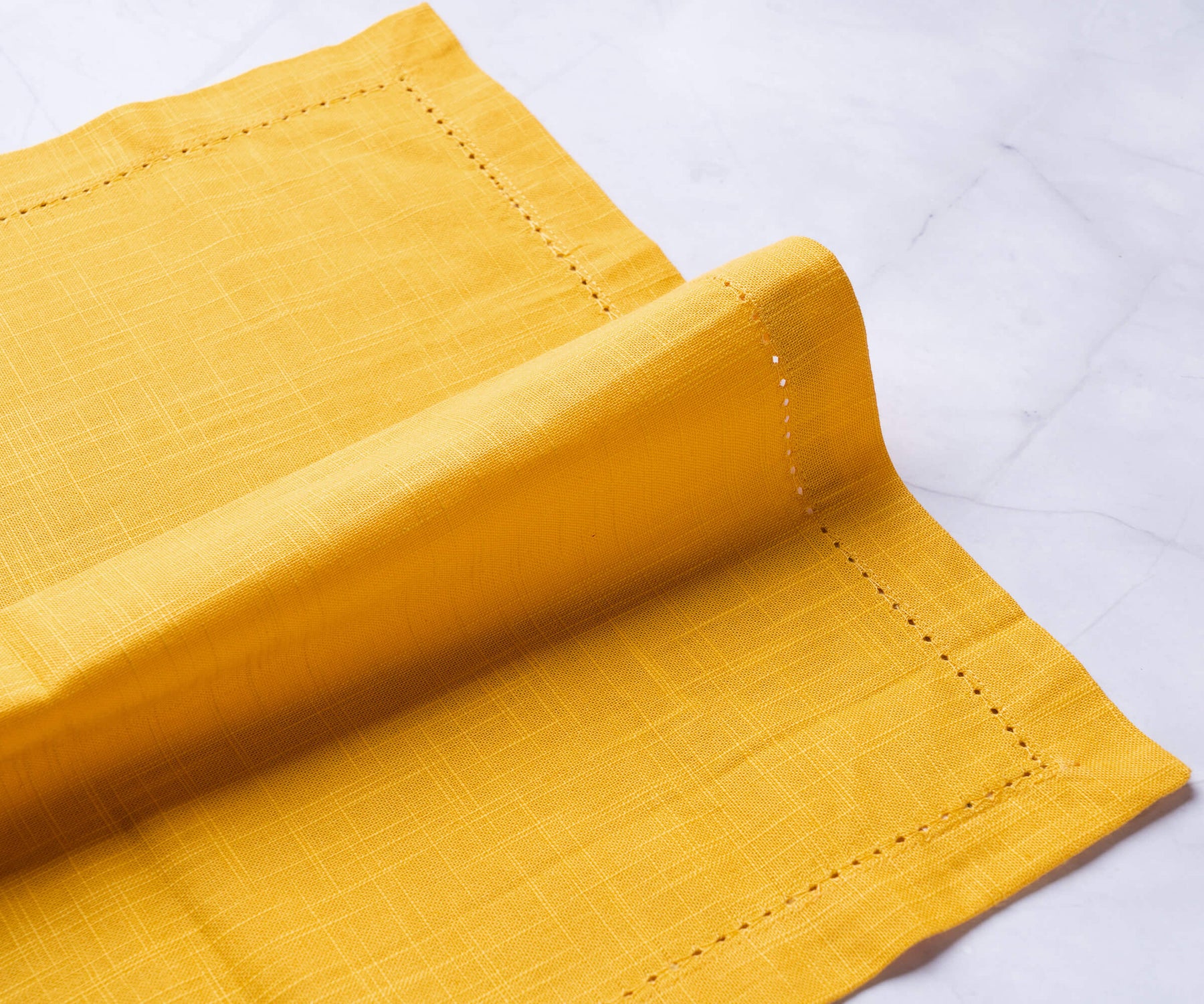 Hemstitched dinner napkins, mustard yellow napkins with a 1-inch border and small folding on the white floor. Hemstitched dinner napkins, mustard yellow napkins with a 1-inch border and small folding on the white floor.