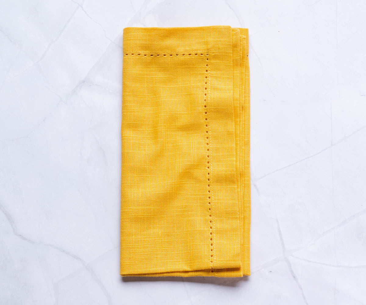 Hemstitched yellow dinner napkins with 1-inch border on the white floor. Hemstitched yellow dinner napkins with 1-inch border on the white floor.